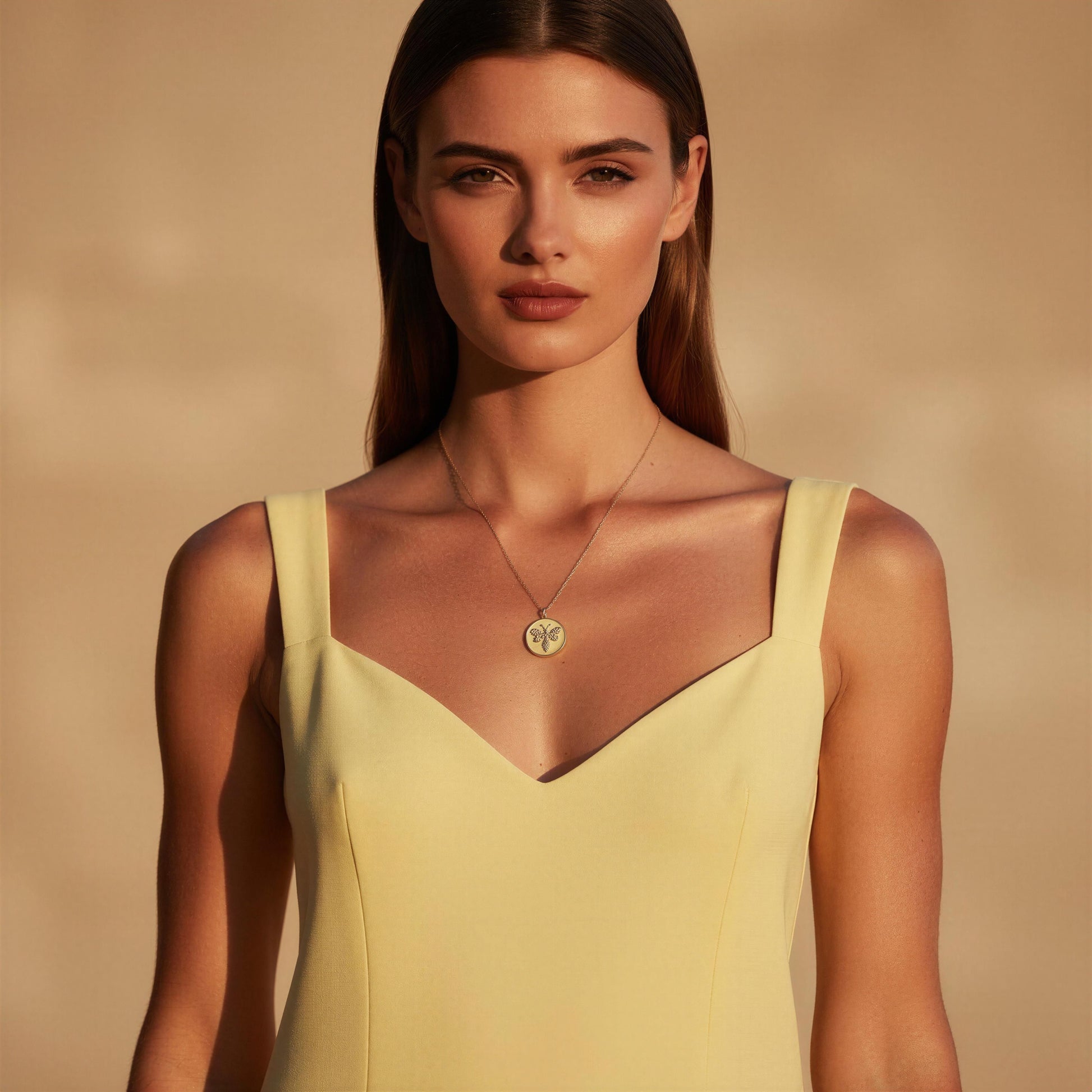Woman wearing a yellow dress against a beige background and the Golden Wasp Medallion Necklace