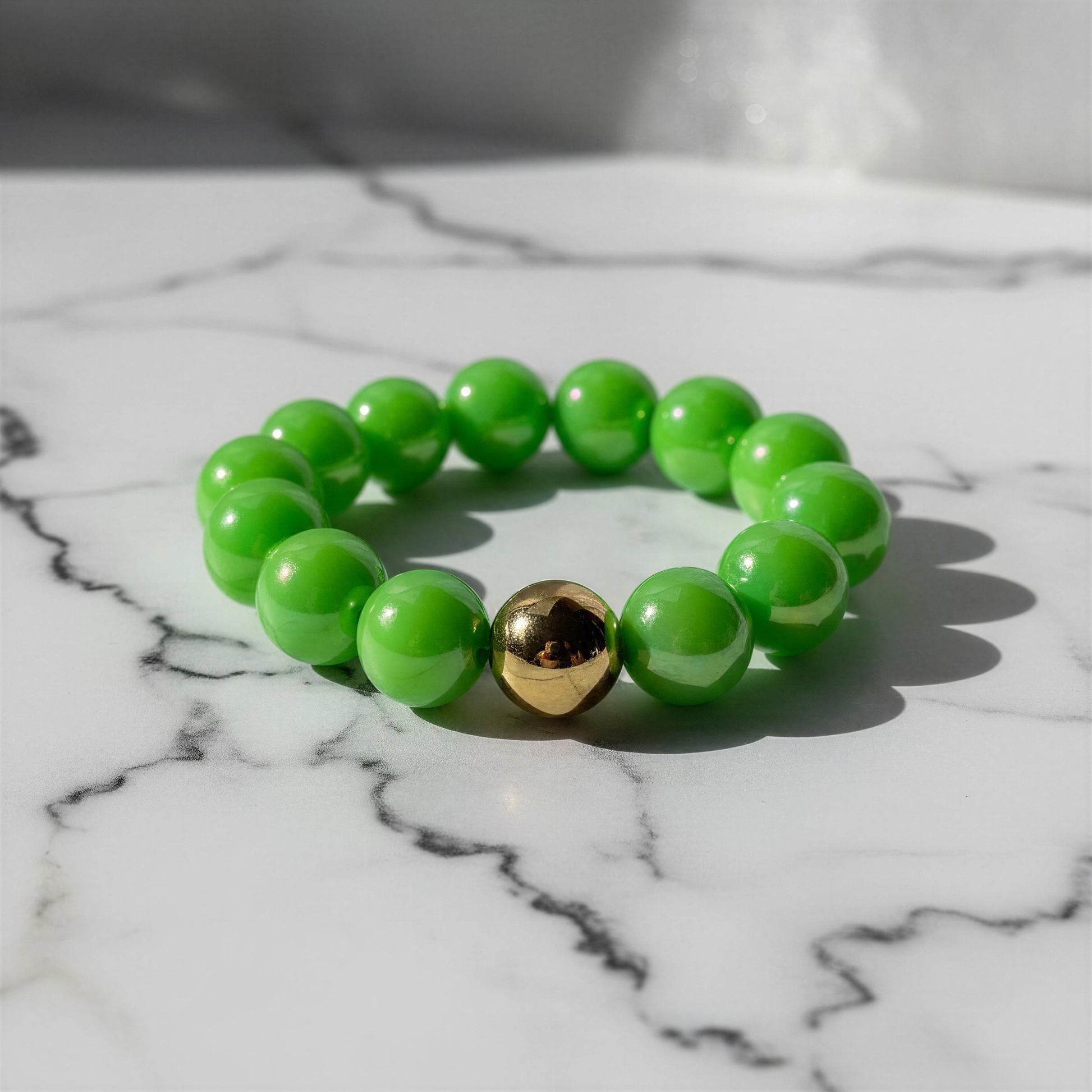 The Green Apple Bracelet with a gold accent on a marble surface