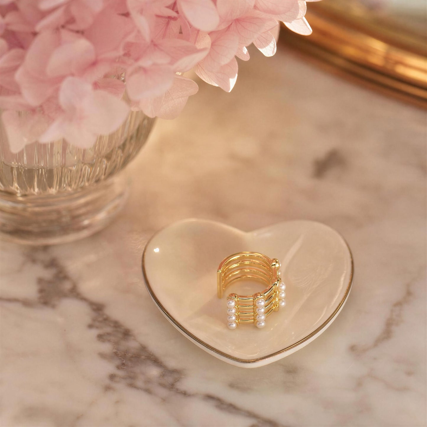 The Grid Pearl Ear Cuff on a heart-shaped dish with pink flowers in the background