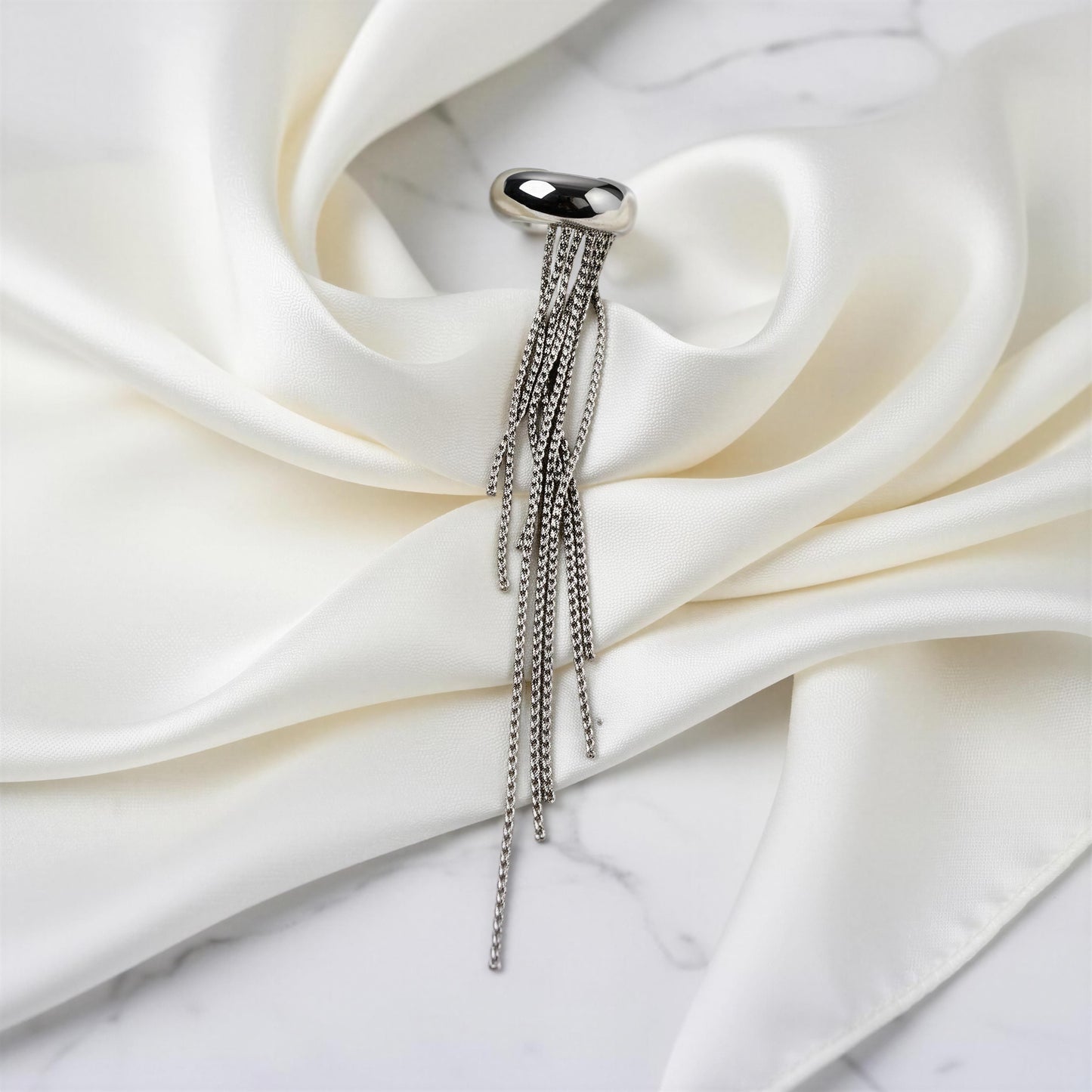 The Vela Silver Ear Cuff on white fabric