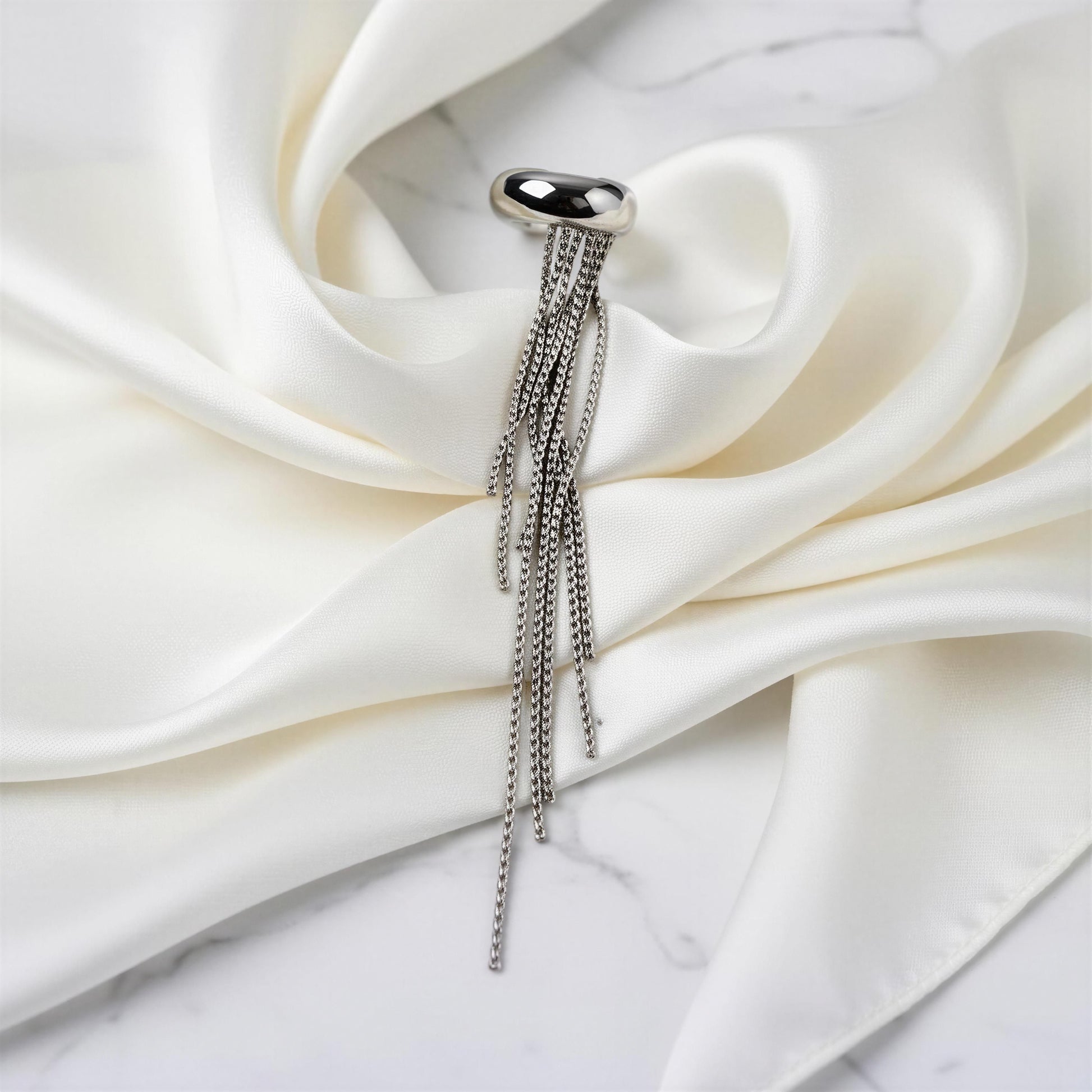 The Vela Silver Ear Cuff on white fabric