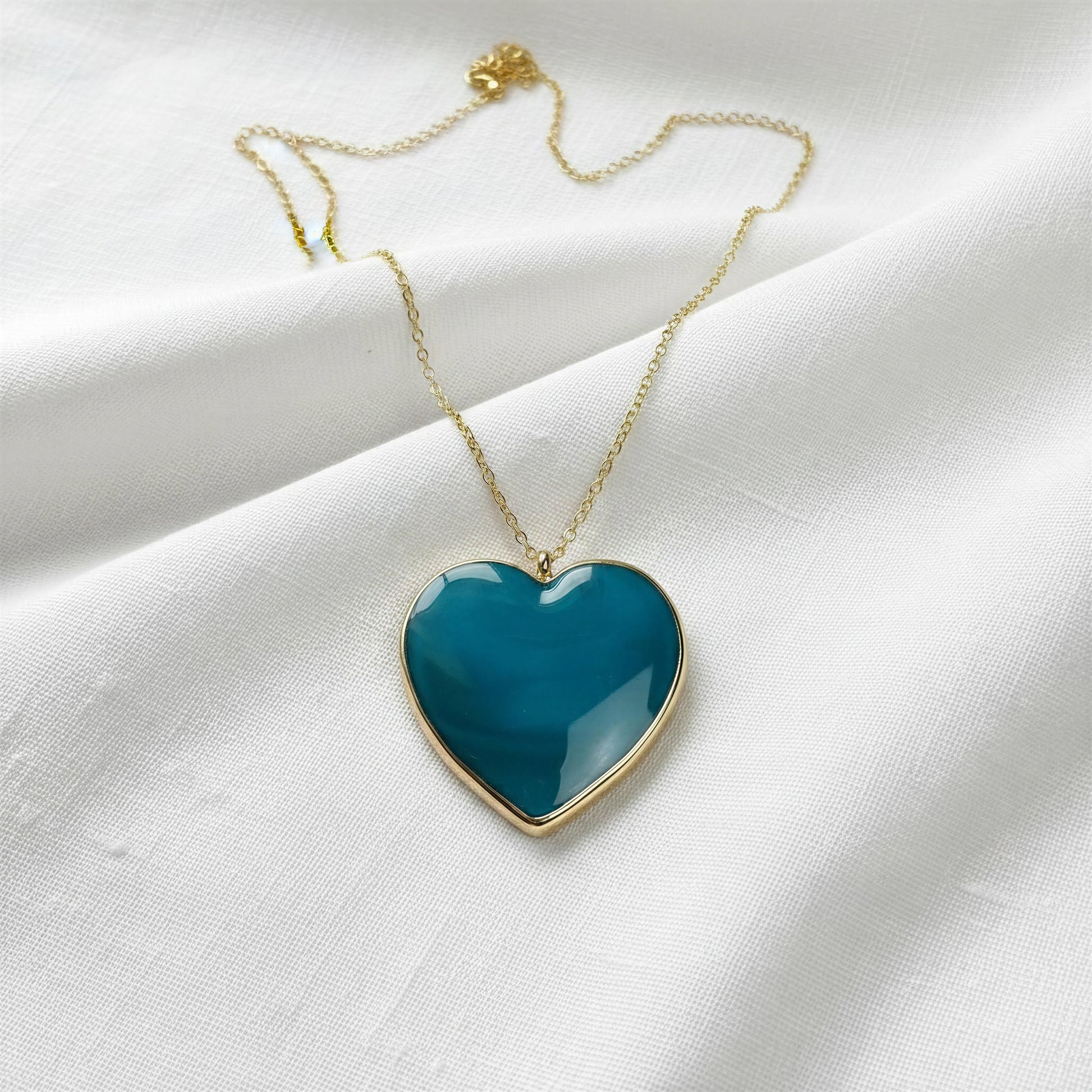 Necklace with a blue heart-shaped pendant on a white fabric background