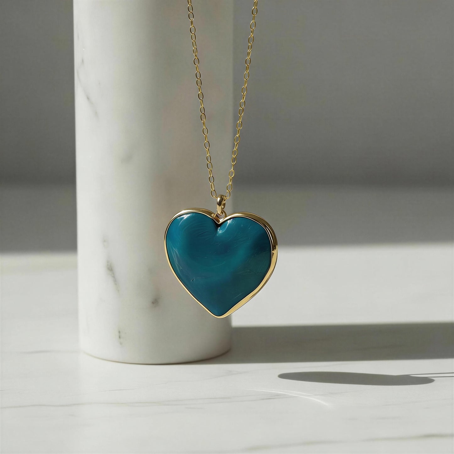 Heart-shaped blue pendant necklace on a marble surface with a neutral background