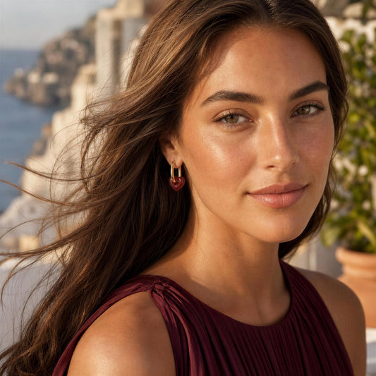 Model wearing the Little Loves Earrings in  Wine Red from Chica Chica Jewelry, set in Mediterranean scenery.