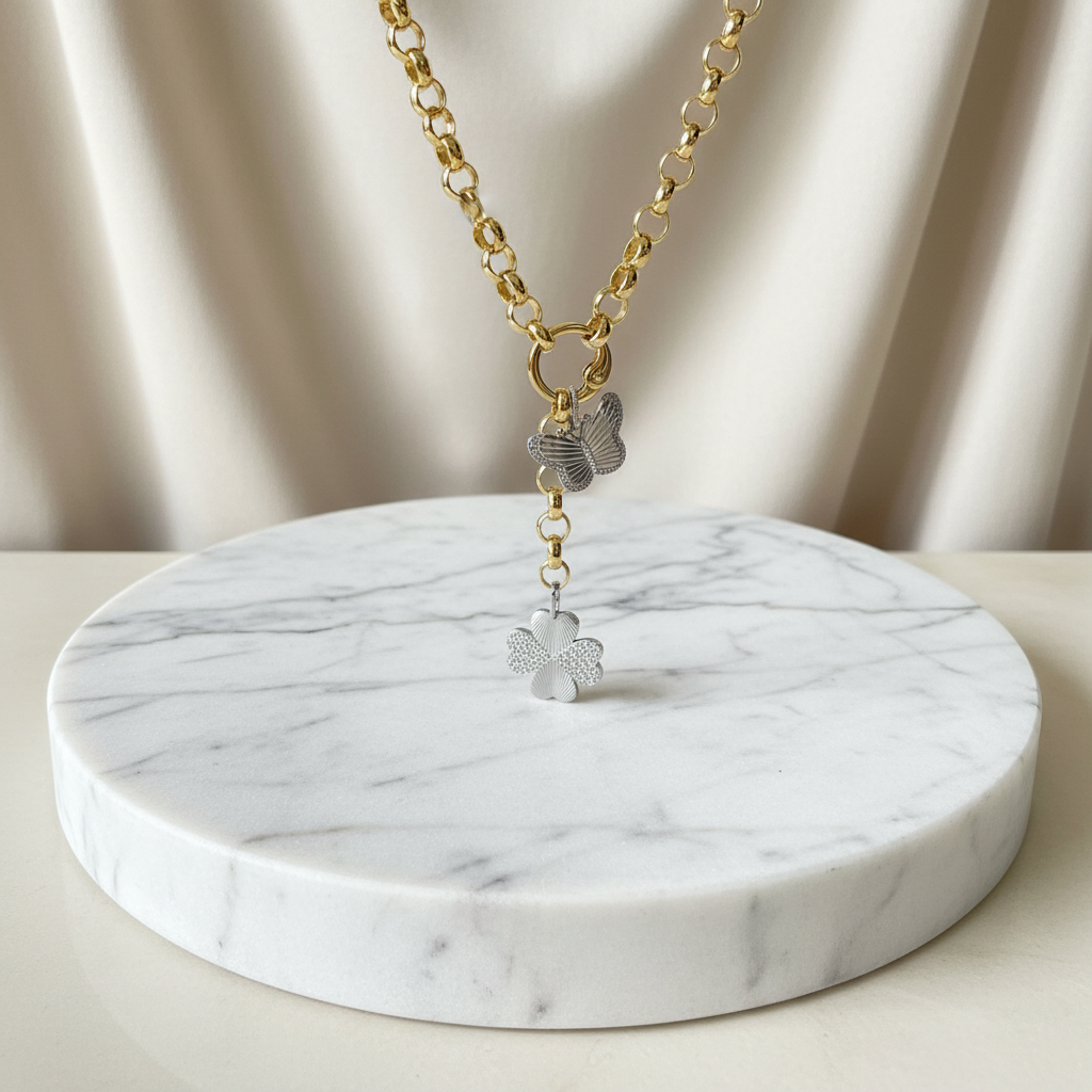 Gold necklace with butterfly pendants on a marble stand against a beige curtain background