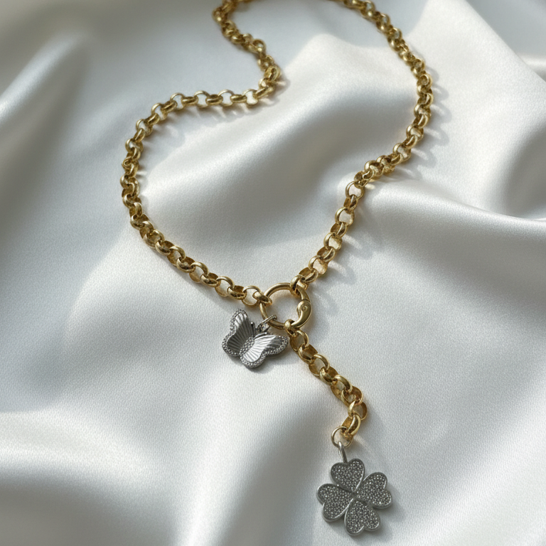 Gold chain necklace with silver pendants on a white fabric background