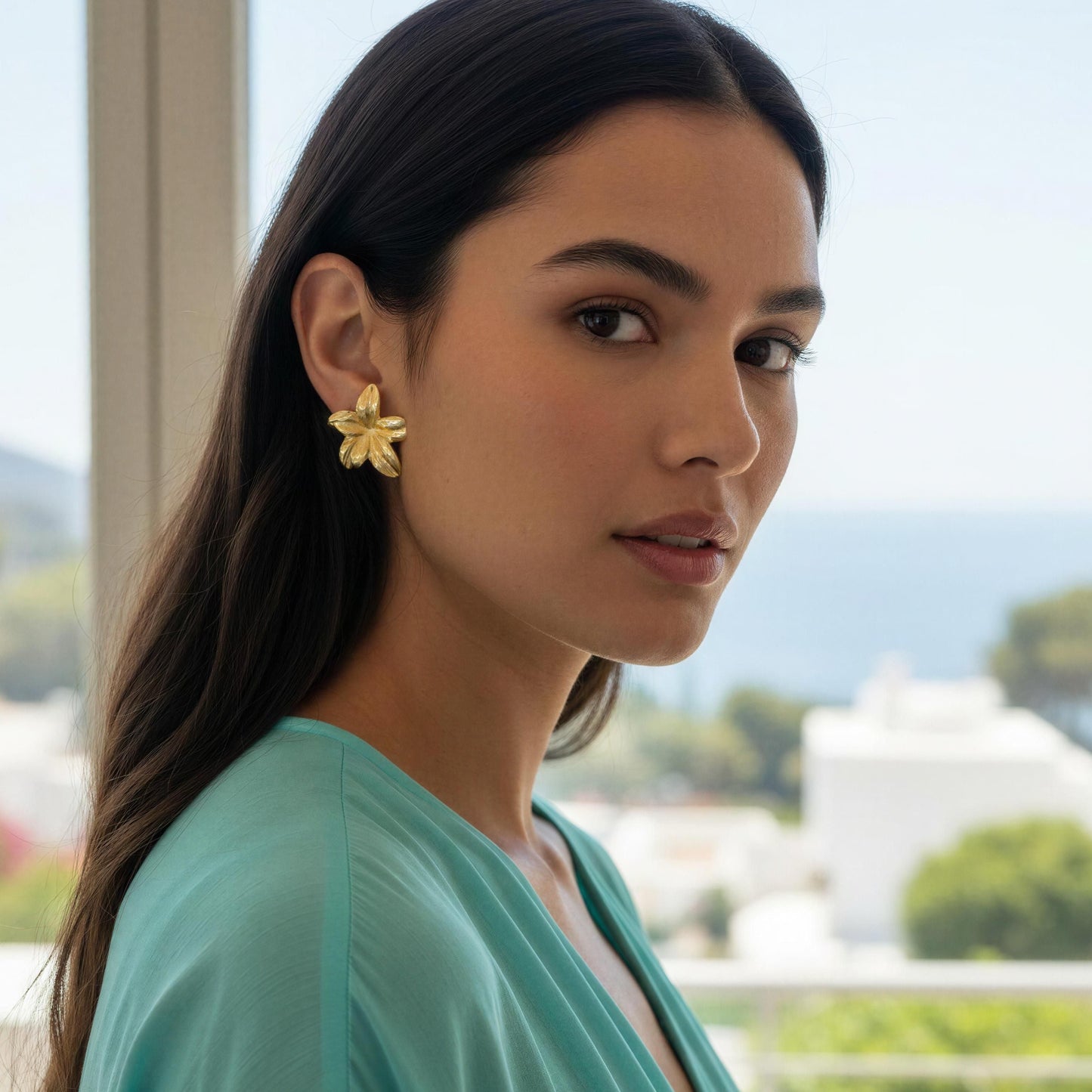Woman wearing the Luna Bloom Earrings - Gold with a scenic background