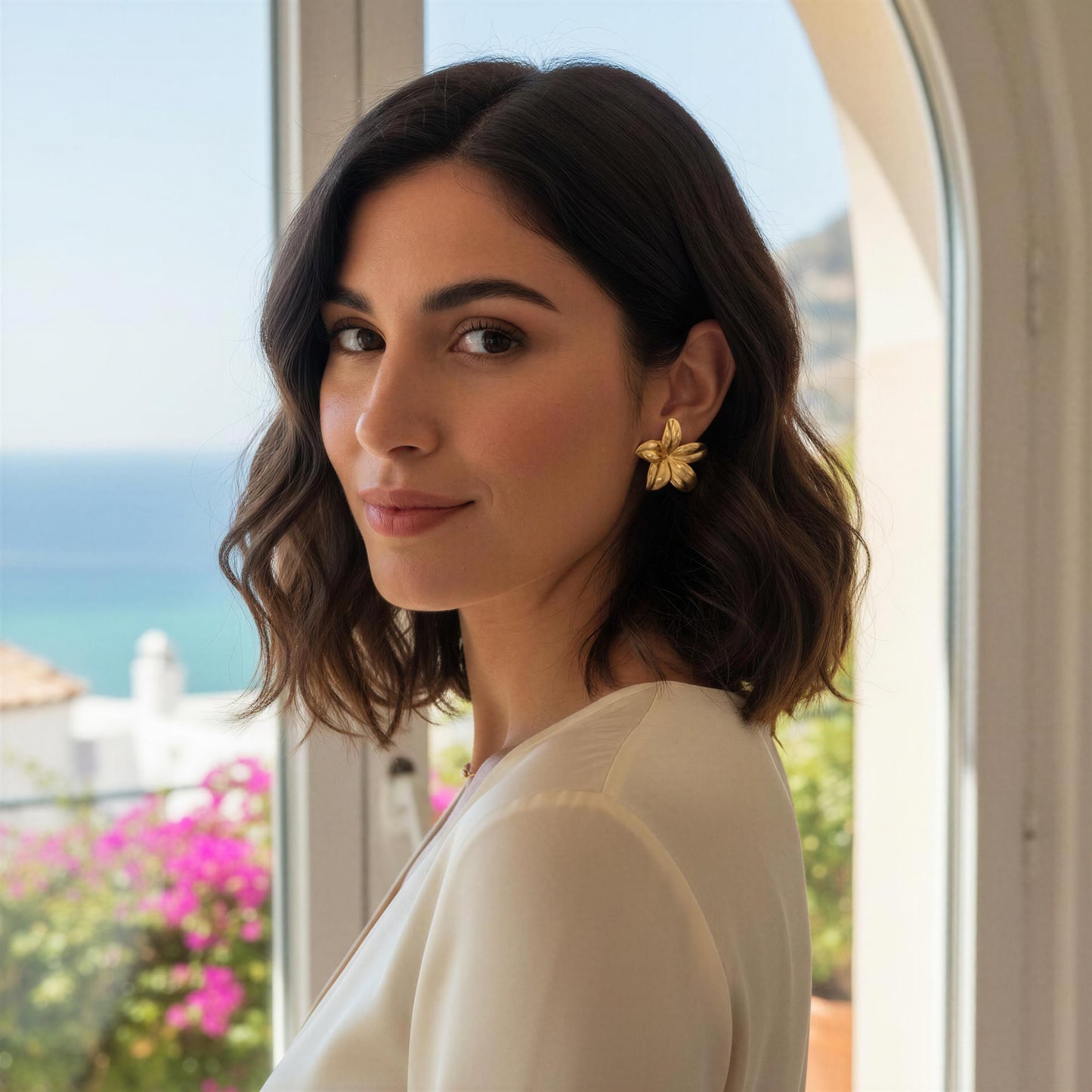 Woman with floral earrings standing by a window with a scenic view