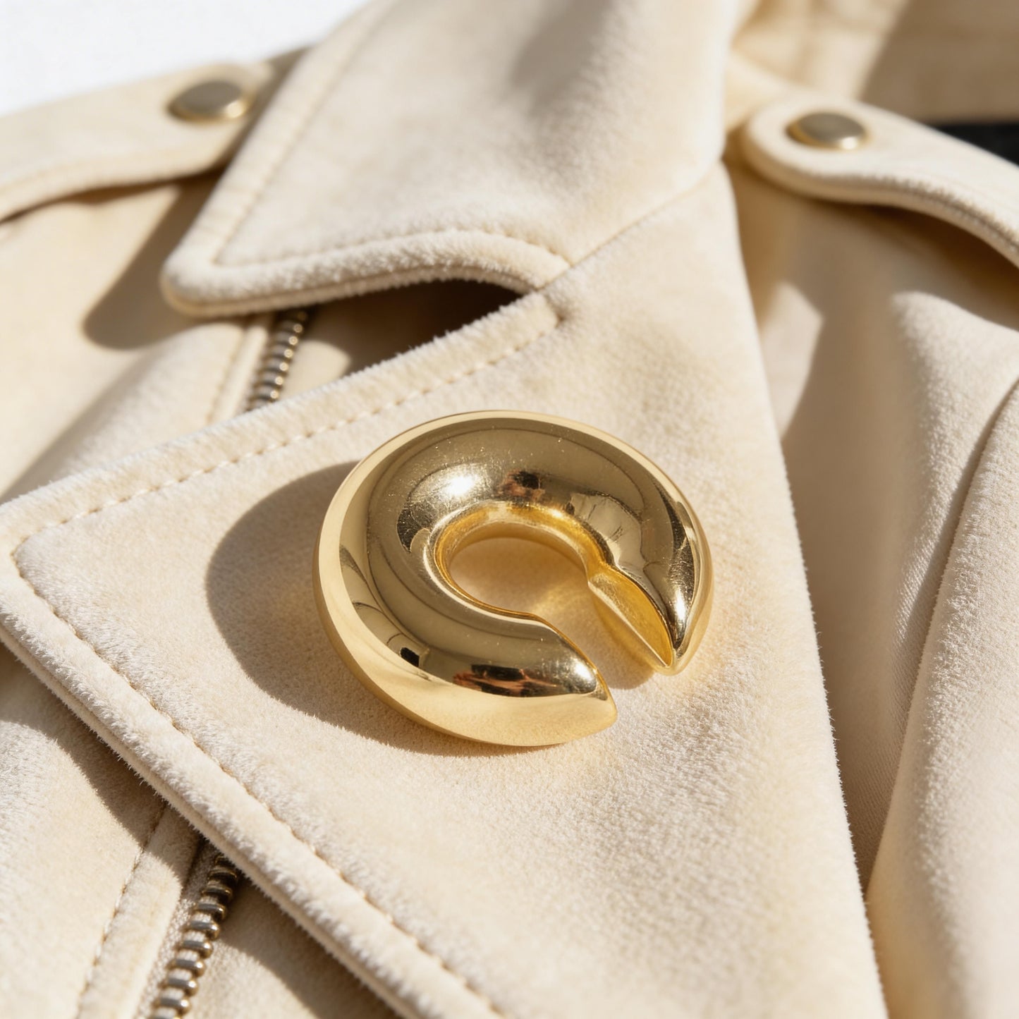 Close-up of a beige coat and the Lunar Orbit Ear Cuff