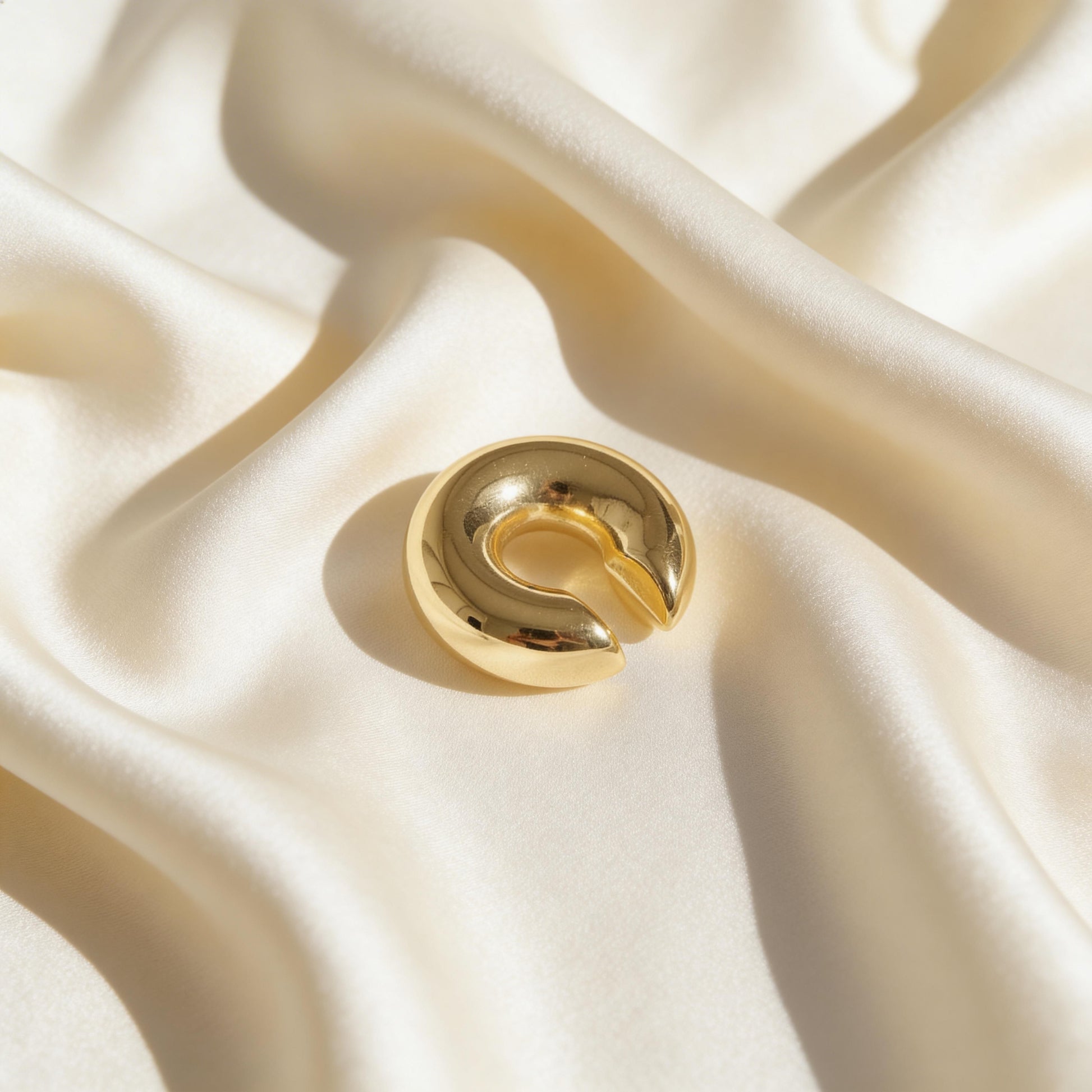 The Lunar Orbit Ear Cuff on a beige fabric background