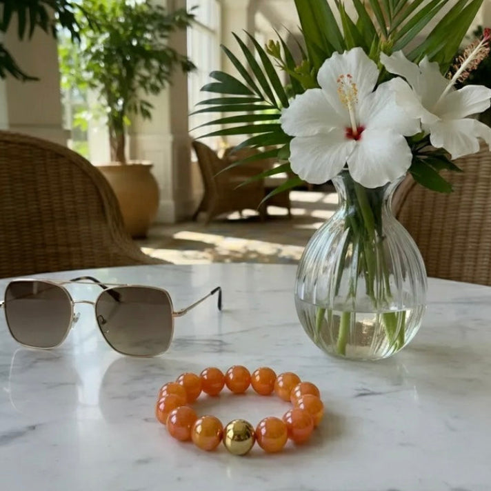 Sunglasses, bracelet, and vase with flowers on a marble table