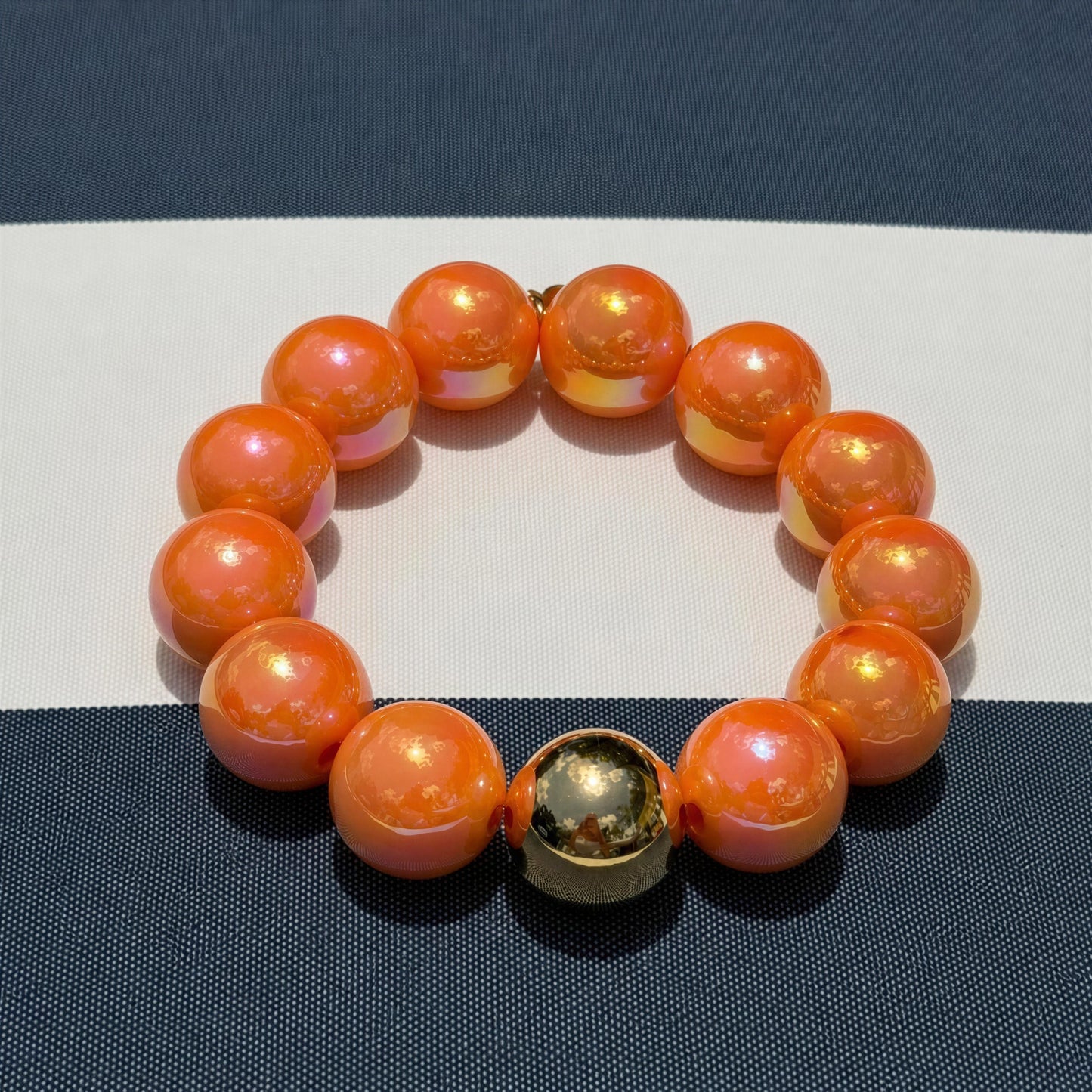 The Mandarin Glow Bracelet from Chica Chica Jewelry  on a white and blue background