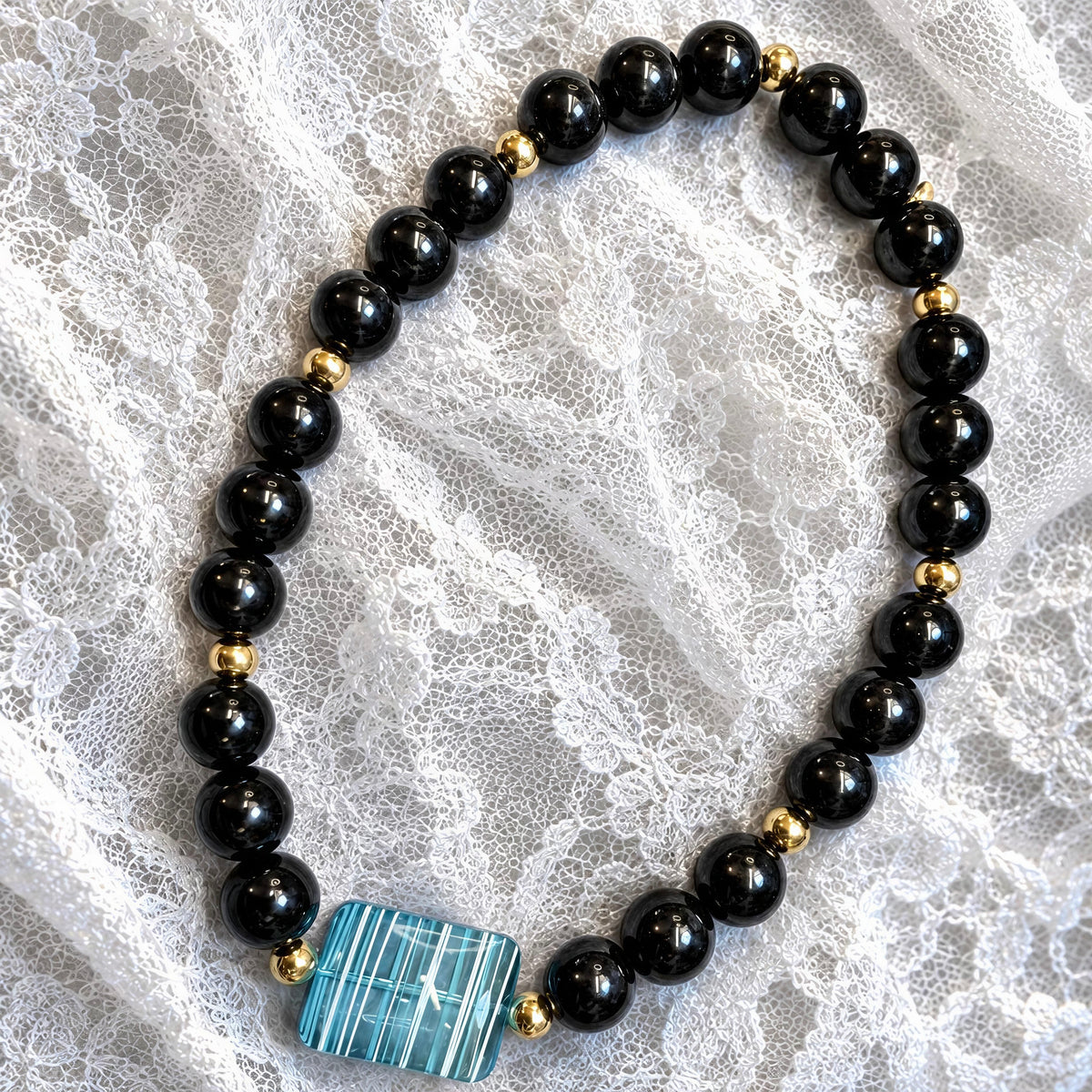 The Mara Necklace from Chica Chica Jewelry  agaisnt white lace fabric.
