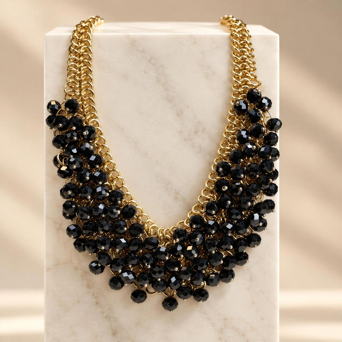 The Marcella Necklace from Chica Chica Jewelry draped from  a tall marble pedestal.  
