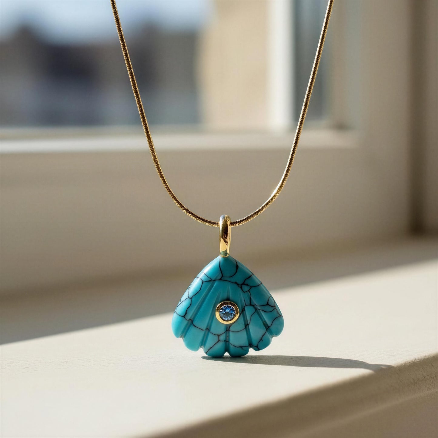 Turquoise pendant necklace with a blue gemstone on a light surface.
