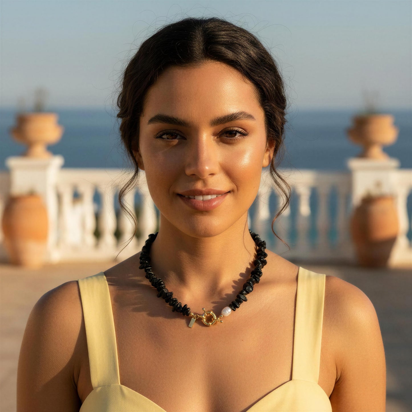 Woman wearing a yellow dress and the Midnight Tide Necklace with a scenic background 