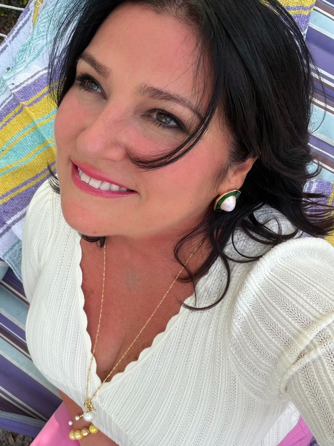Founder of Chica Chica Jewelry wearing a white top with a colorful background