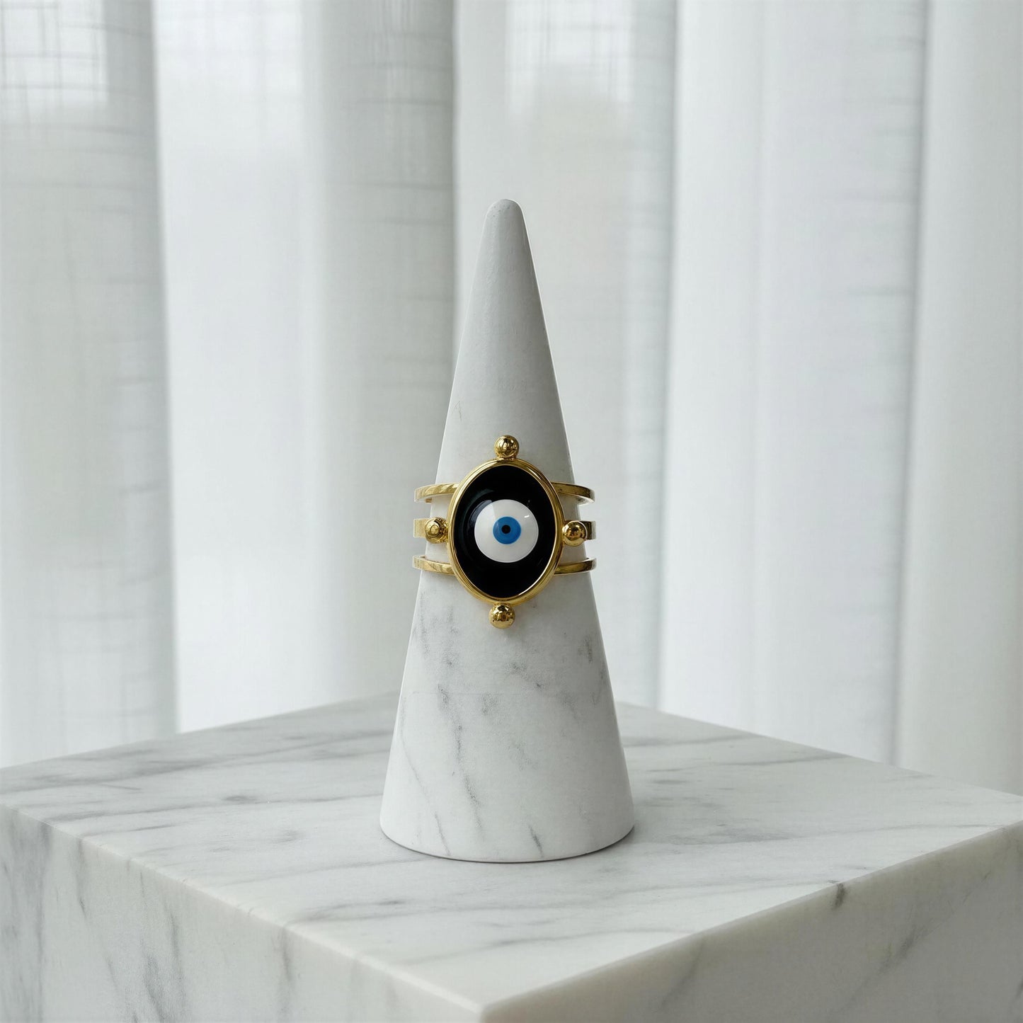 TheNazar Aura Ring on a marble cone against a white curtain background