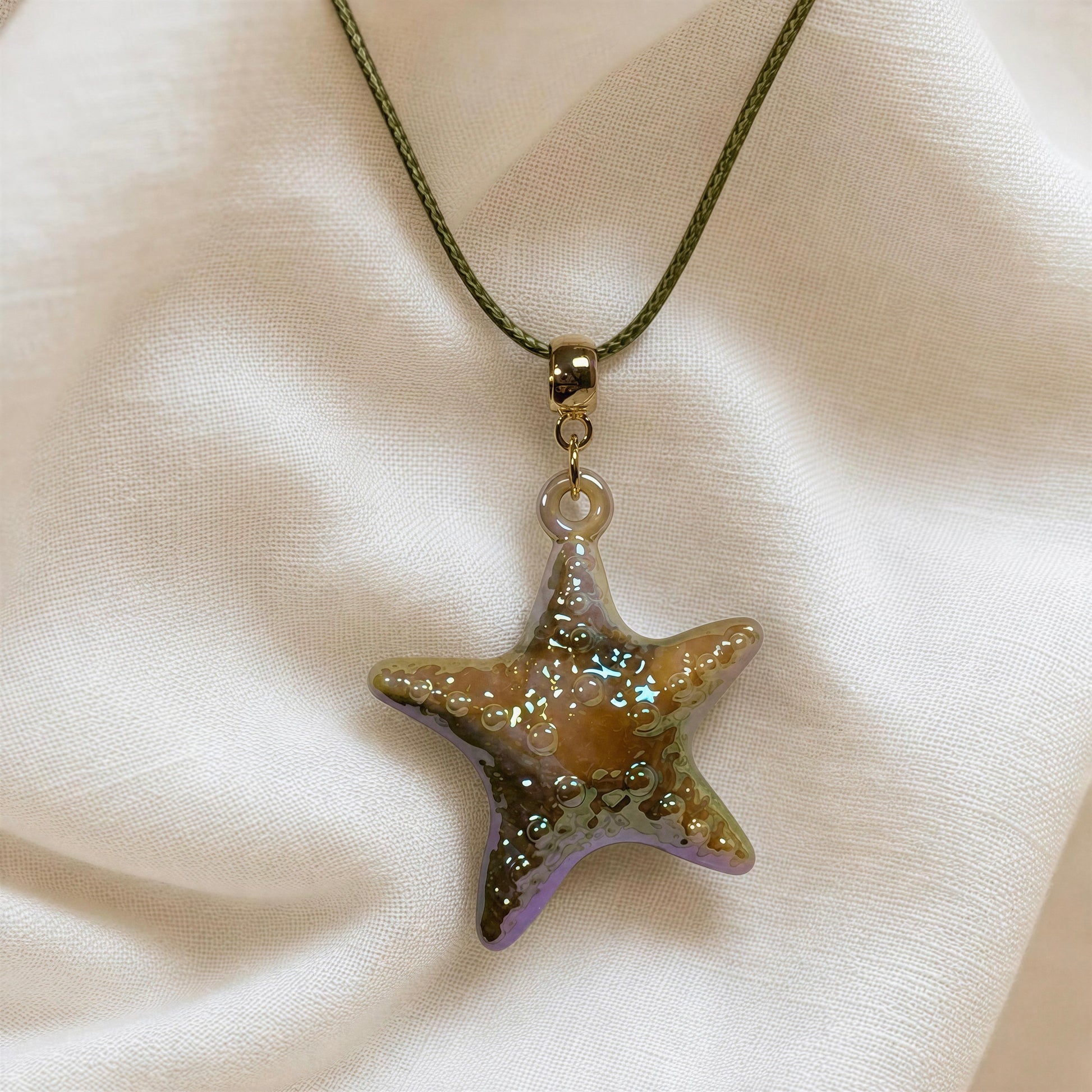 The Nerina Olive Necklace draped from beige linen fabric.