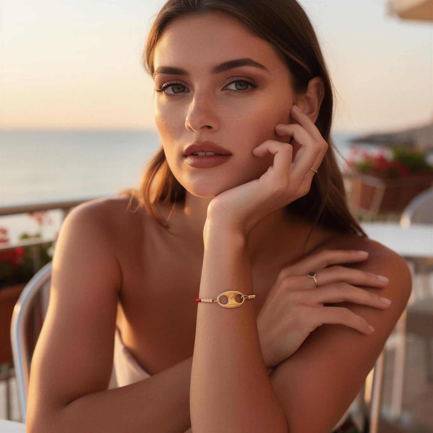 Woman with Nexo Bracelet in red sitting by a waterfront at sunset