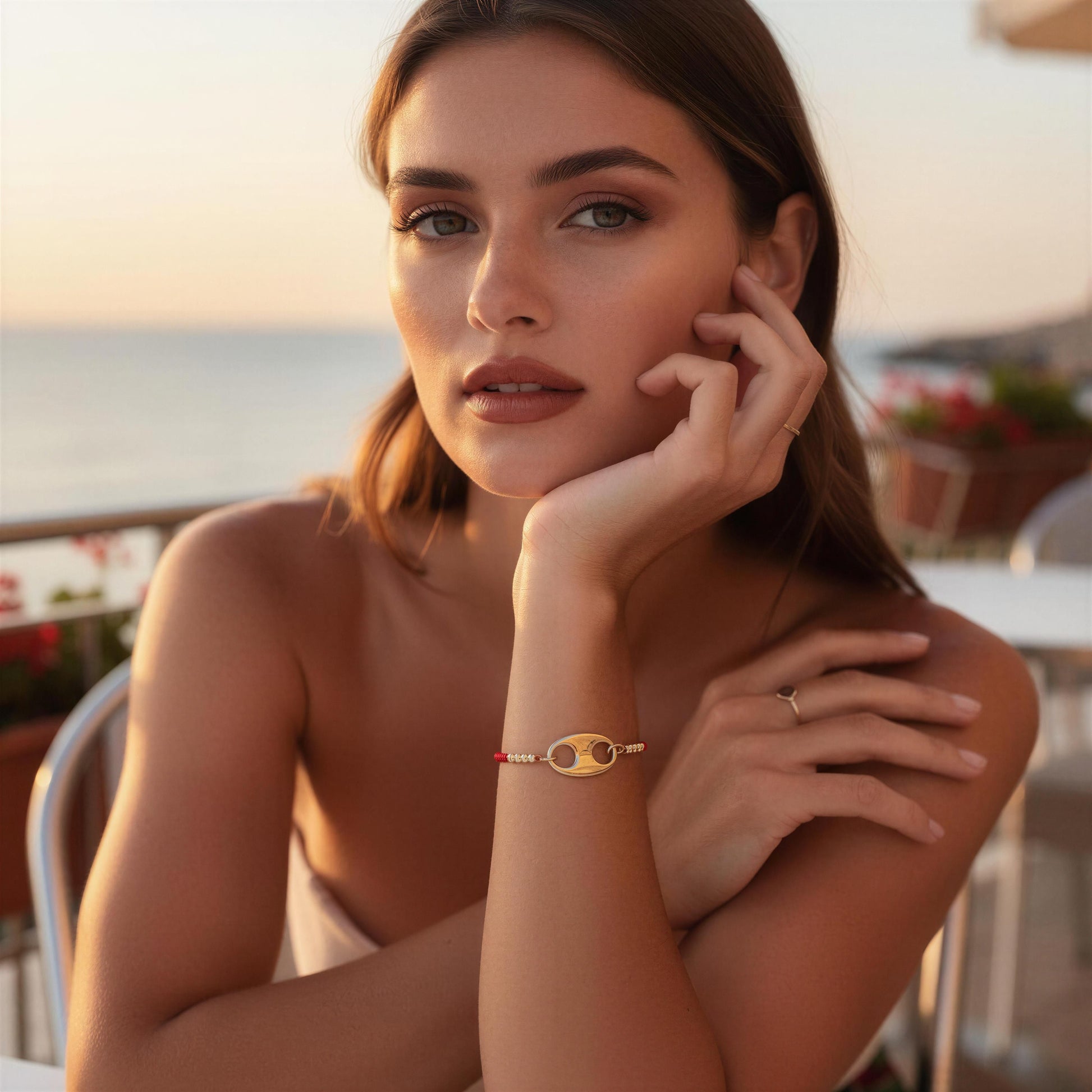 Woman with Nexo Bracelet in red sitting by a waterfront at sunset