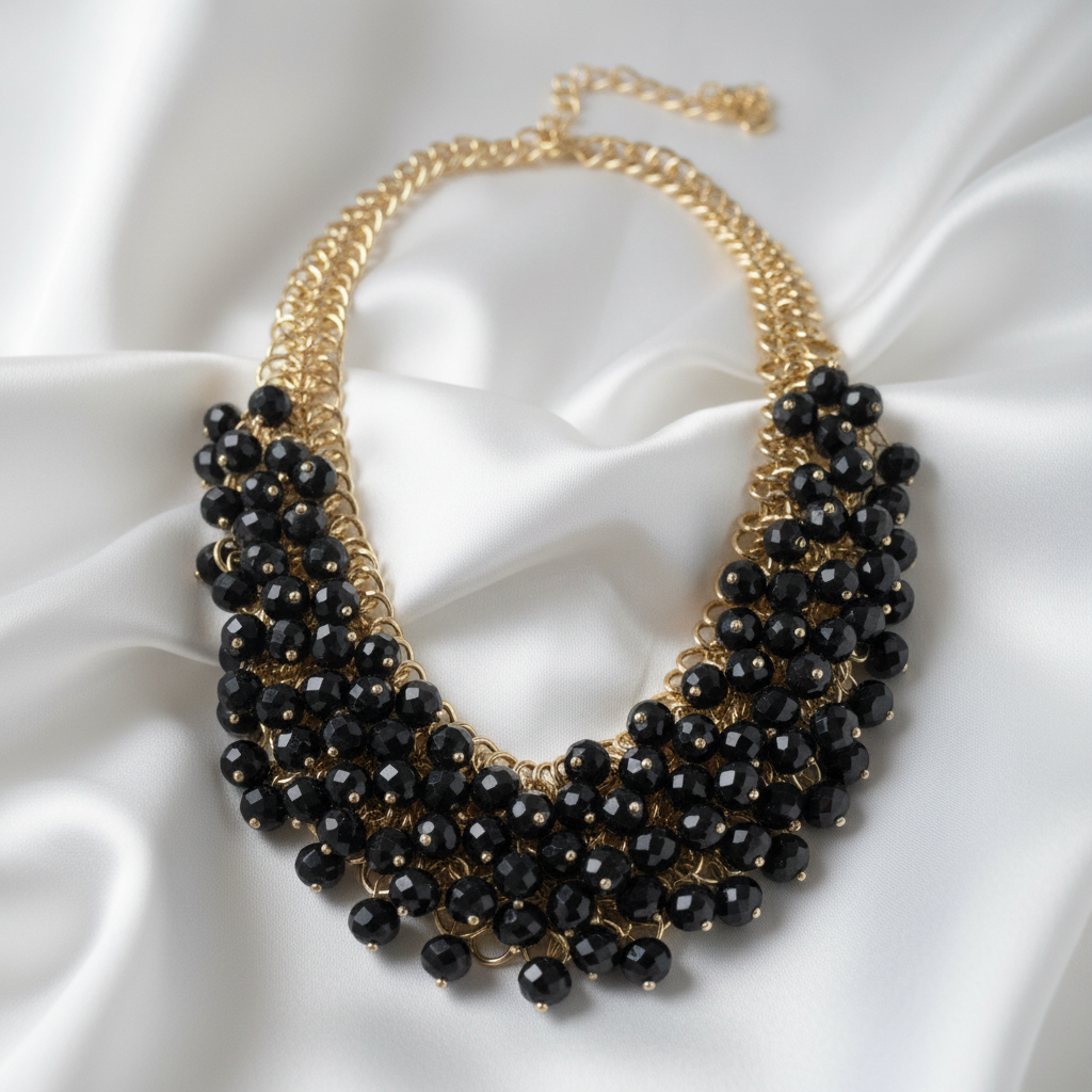 Black beaded necklace -Obsidian Mist Necklace form Chica Chica Jewelry -with gold chain on a white satin background