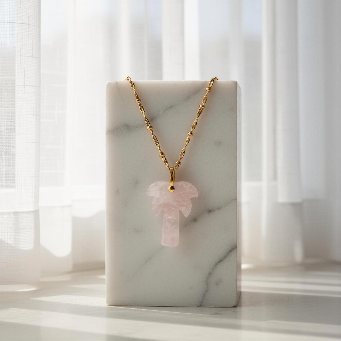 The  Palma Rosa Long Necklace on a marble stand with a soft, blurred background