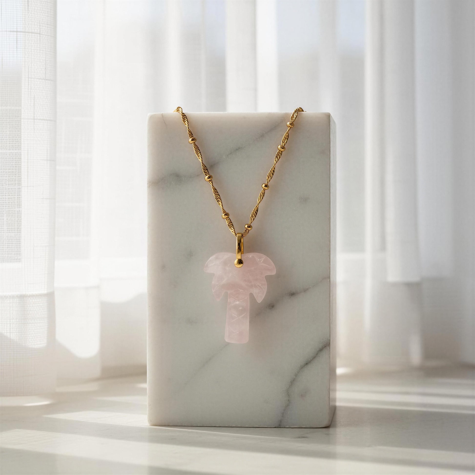 The  Palma Rosa Long Necklace on a marble stand with a soft, blurred background