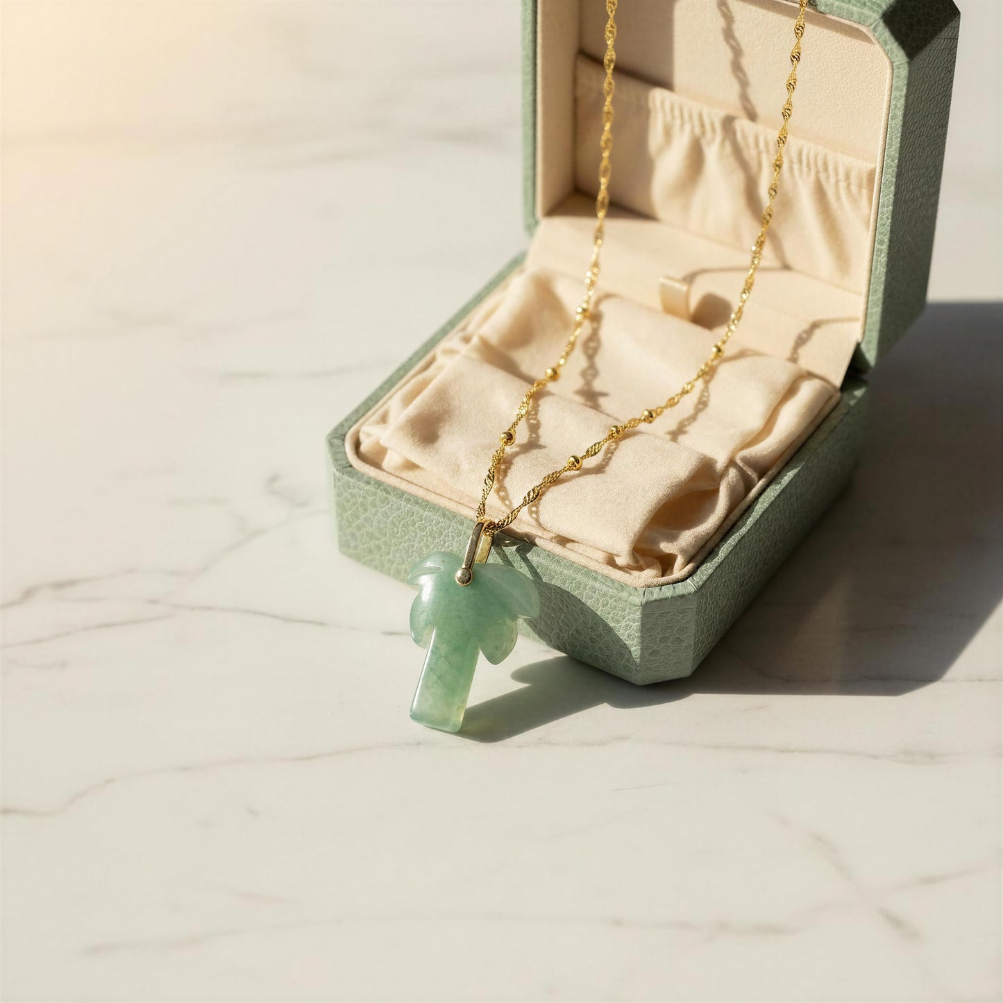 The Palma Verde Long Necklace in an open jewelry box on a light surface