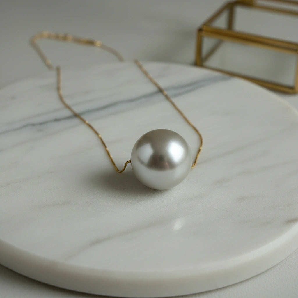 The Perla Statement Necklace  on a marble surface with a gold box in the background