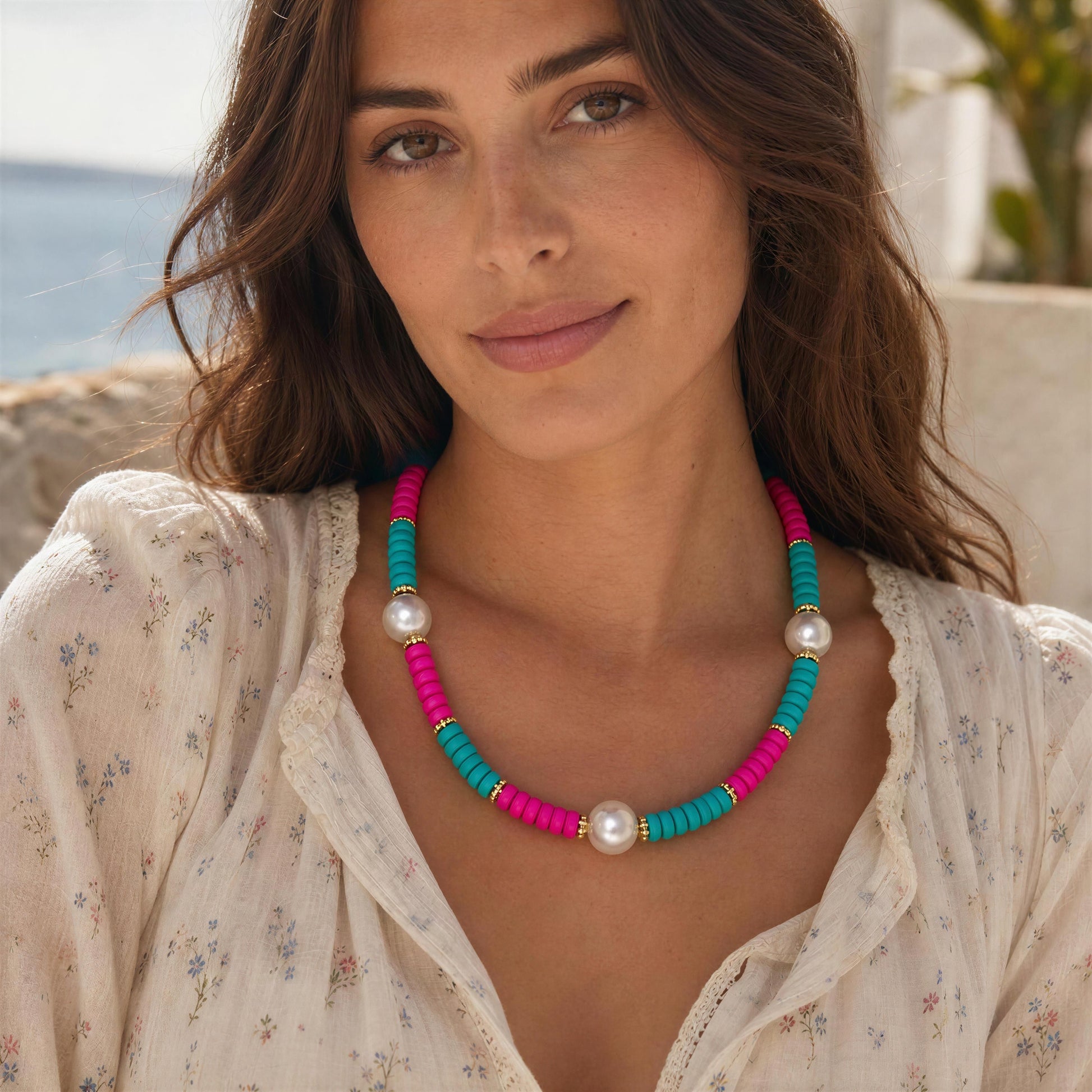 Woman wearing the Persiana Necklace with a blurredMediterranean coastal background