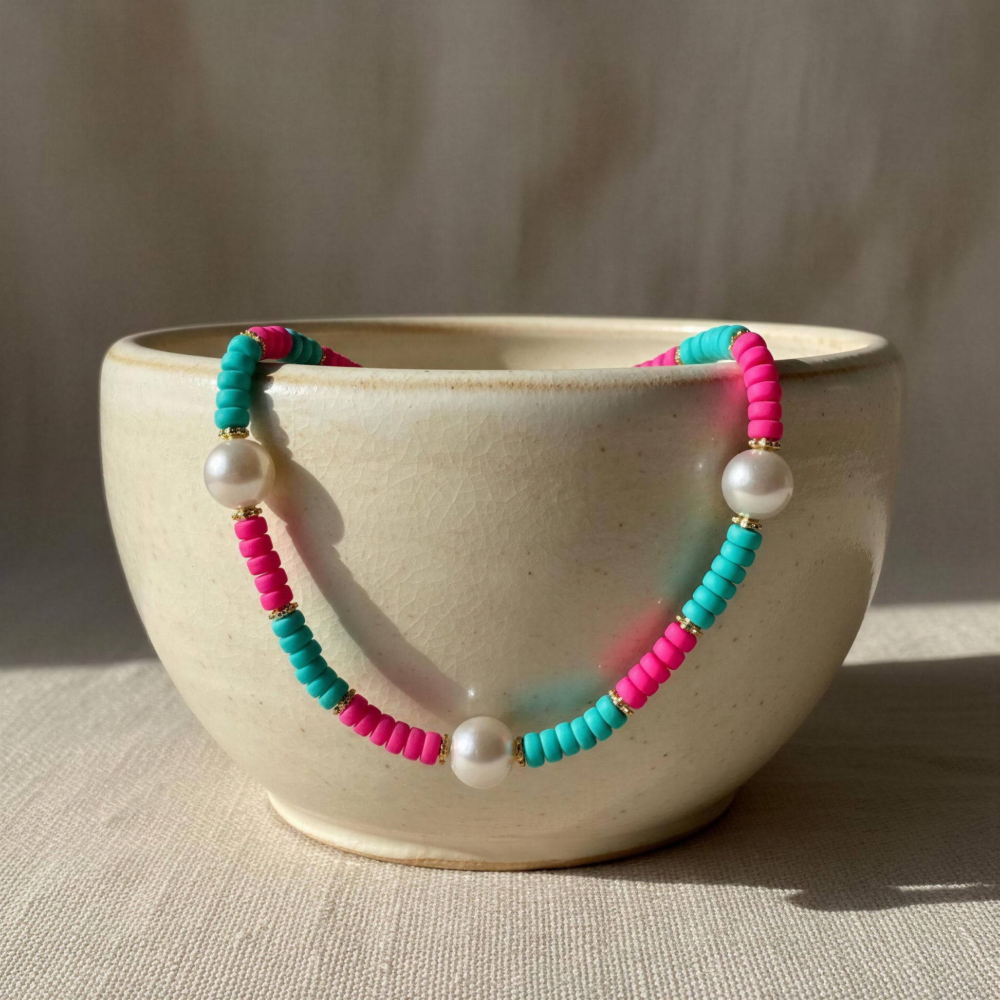 Colorful beaded necklace with pearls on a beige ceramic bowl