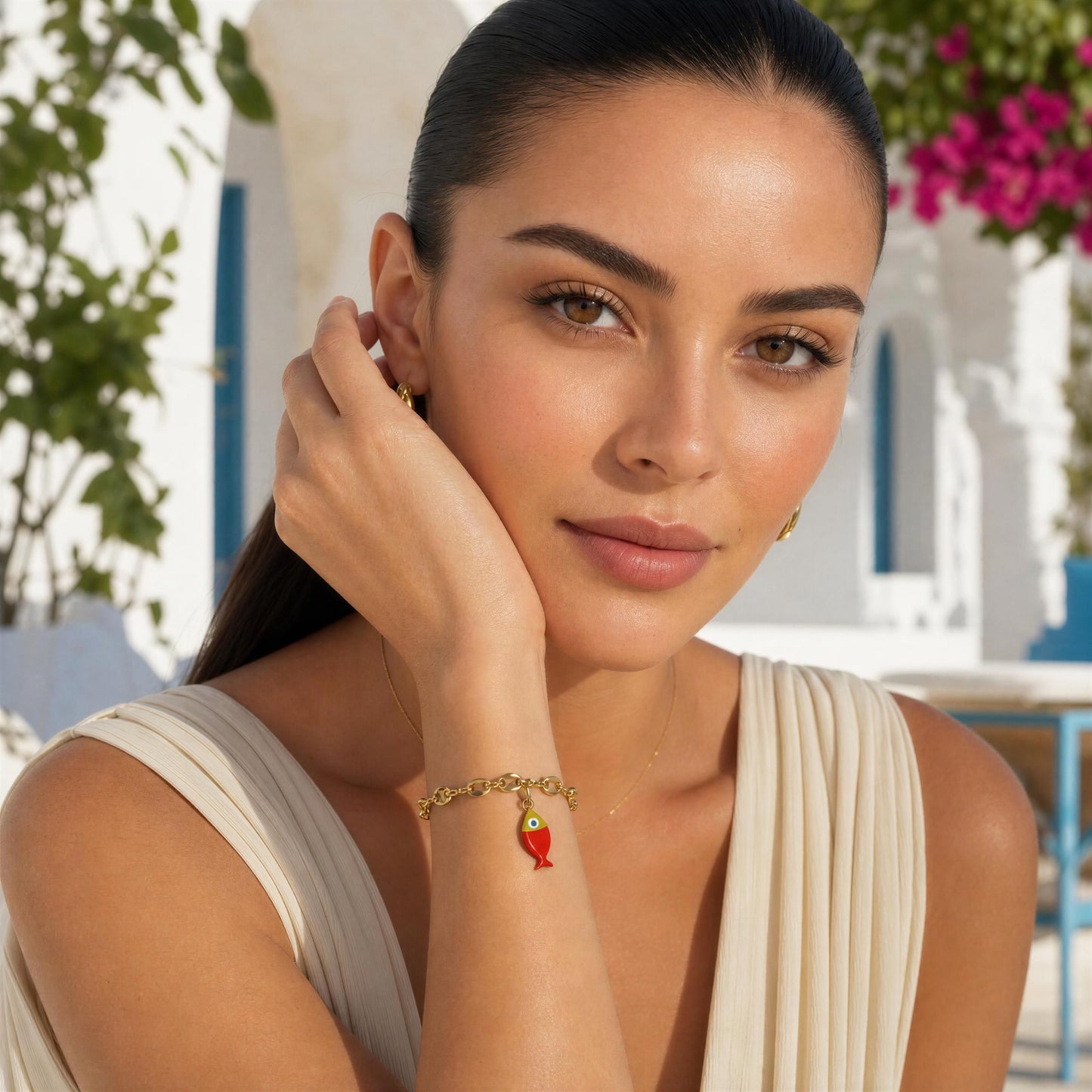 Woman wearing a gold bracelet with a fish charm in an outdoor setting