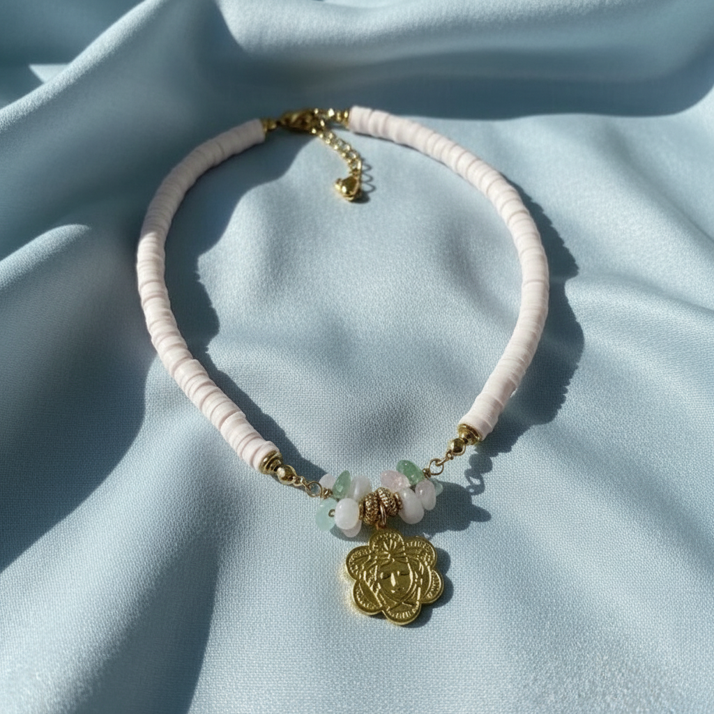 Pure Beauty Necklace with pink beads and gold accents on a light blue fabric background