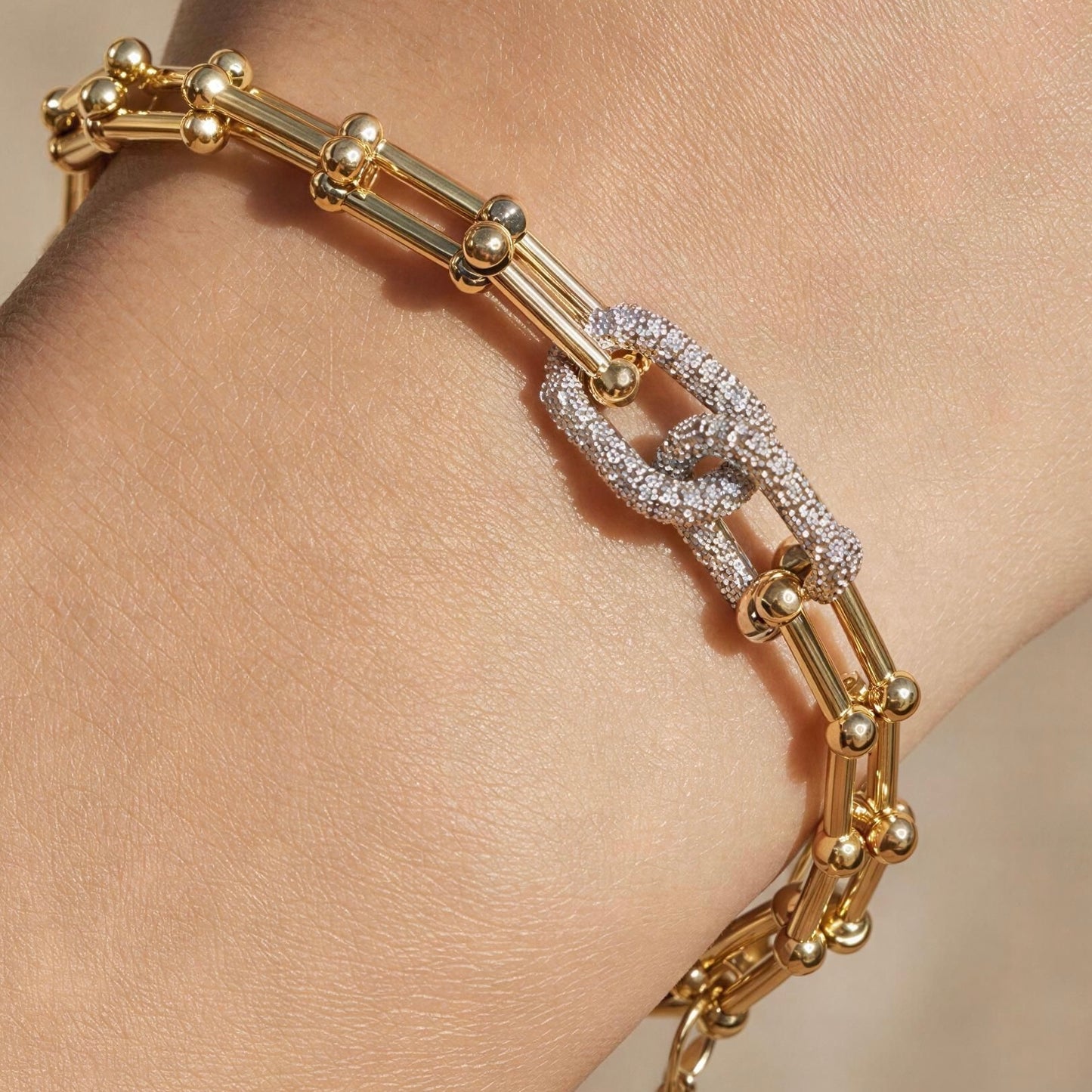Radiance Link Bracelet with 18K gold-plated links and silver-tone pavé zircon centerpiece, shown worn on a person's wrist.