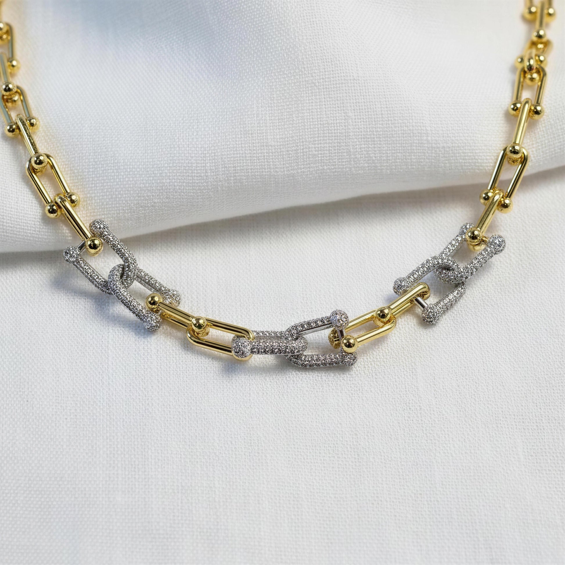 The Radiance Link Necklace from Chica Chica Jewelry against white fabric.