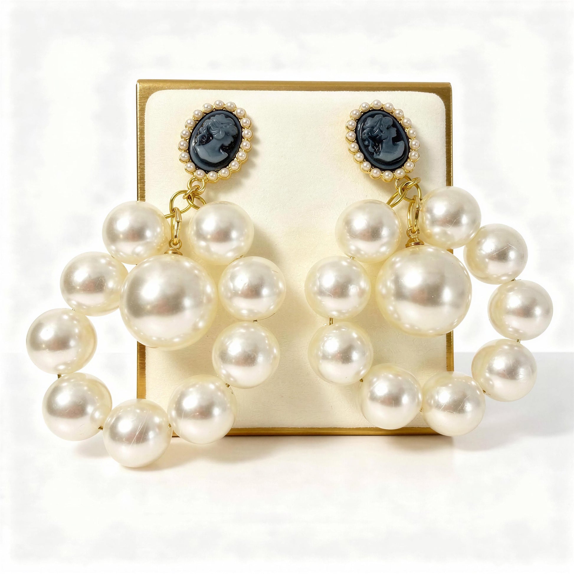The Regal Cameo Pearl Statement Earrings on a gold display card against a white background