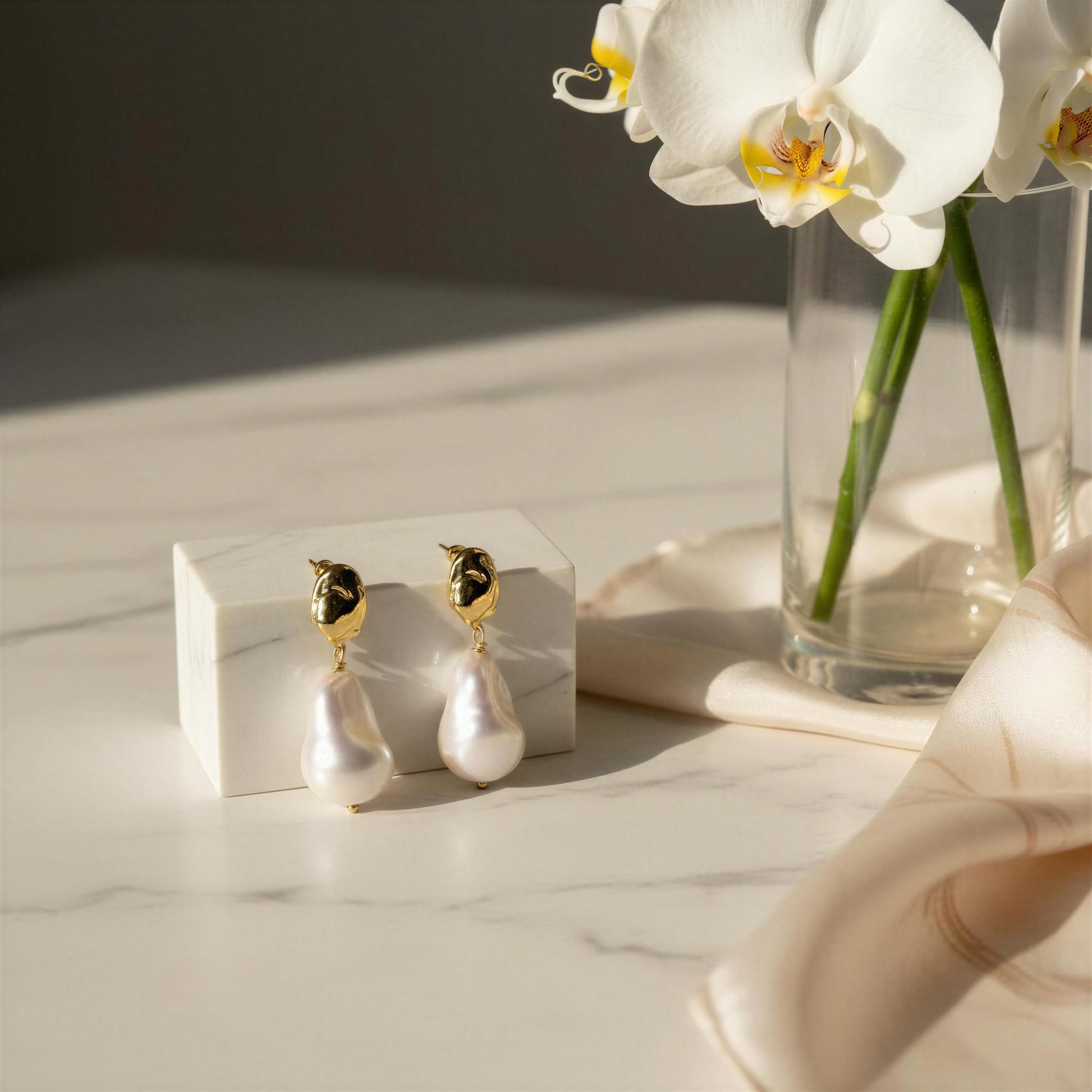The Bellina_Pearl_Drop_Earrings_ from _Chica_Chica_Jewelry on white marble table beside an orchids vase and scarf.