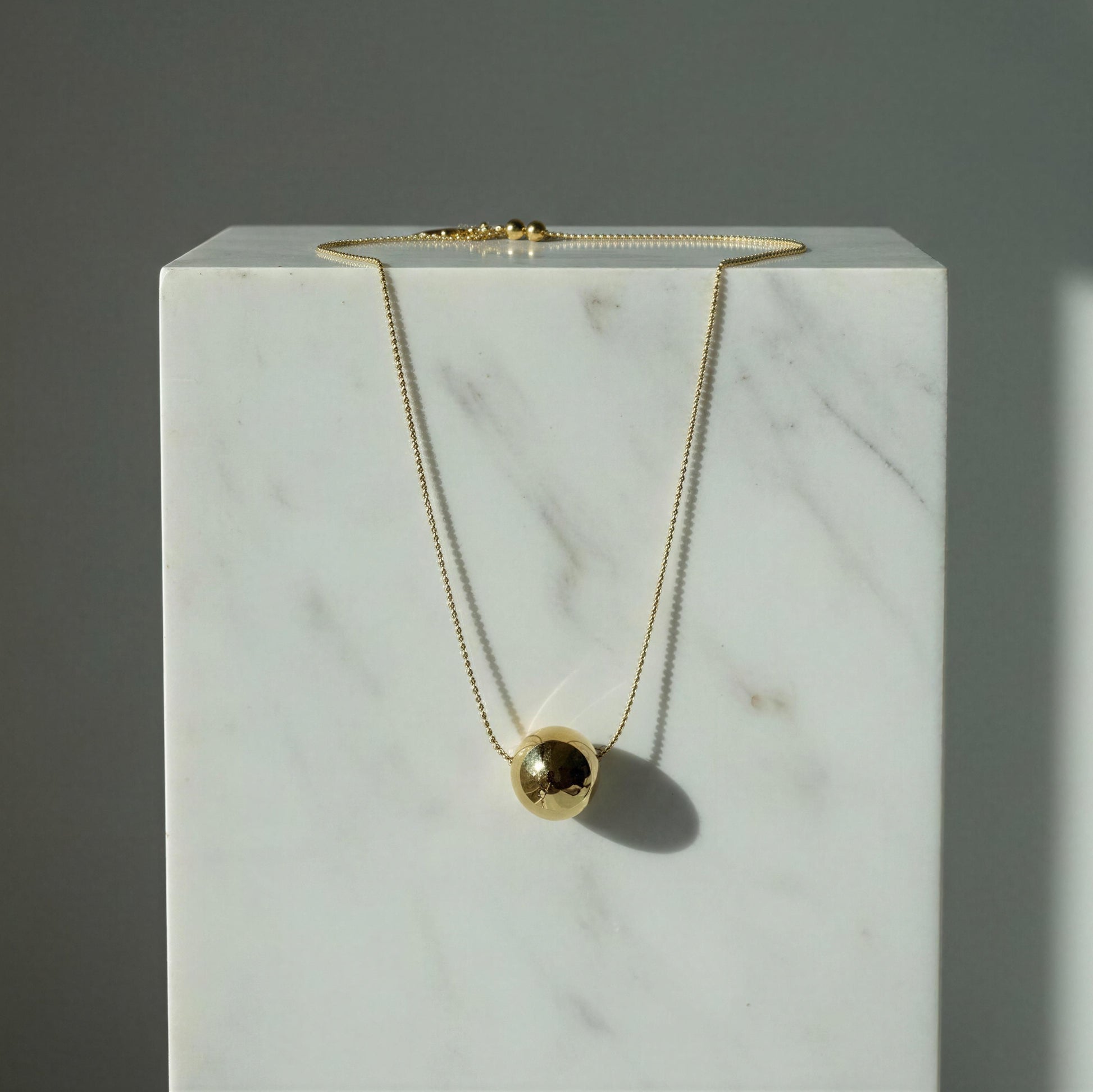 The Riviera Orb Necklace on a marble surface