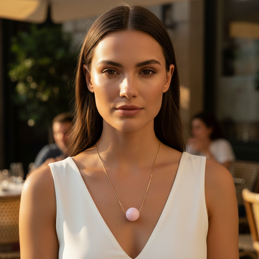 Woman wearing a white sleeveless top with the Rosé Sphere Statement Necklace in an outdoor setting