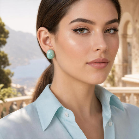 Woman wearing light blue shirt and the Rosina Studs in Aqua Glow with blurred outdoor background