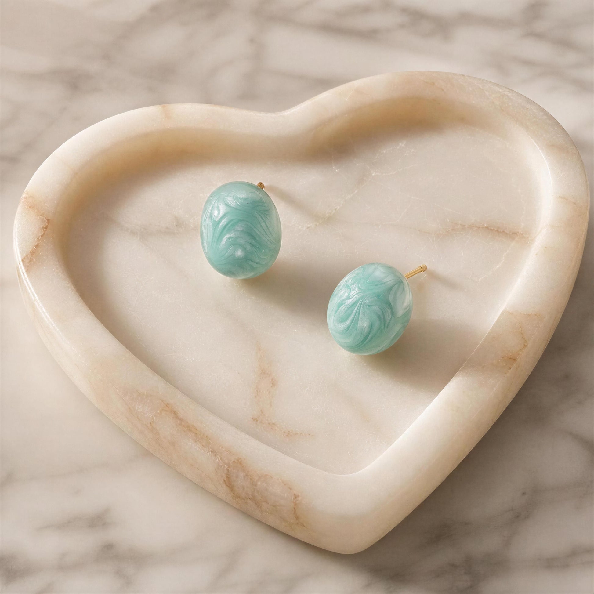 The Rosina Studs -Aqua Glow on a heart-shaped marble dish