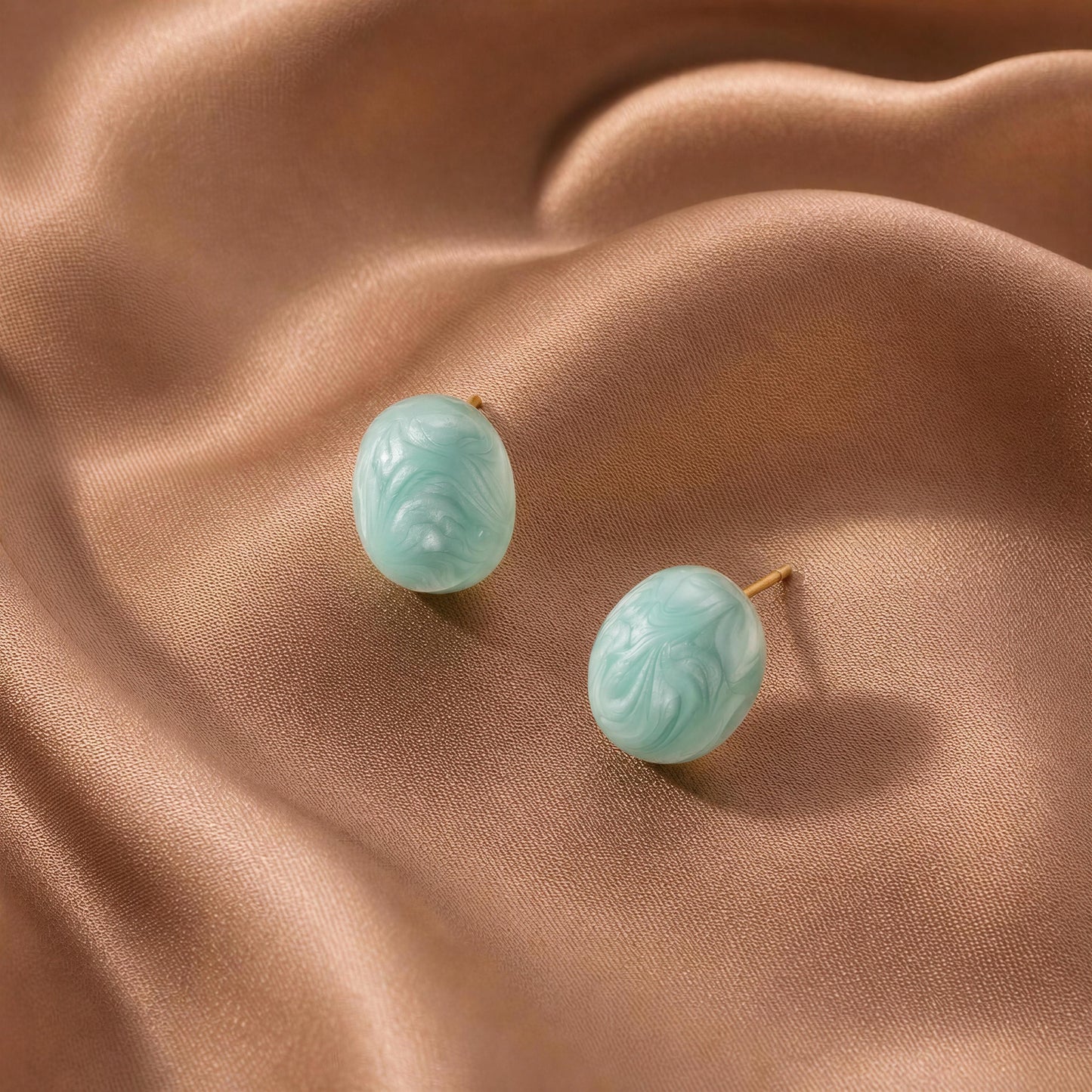 Pair of turquoise earrings on a beige fabric background