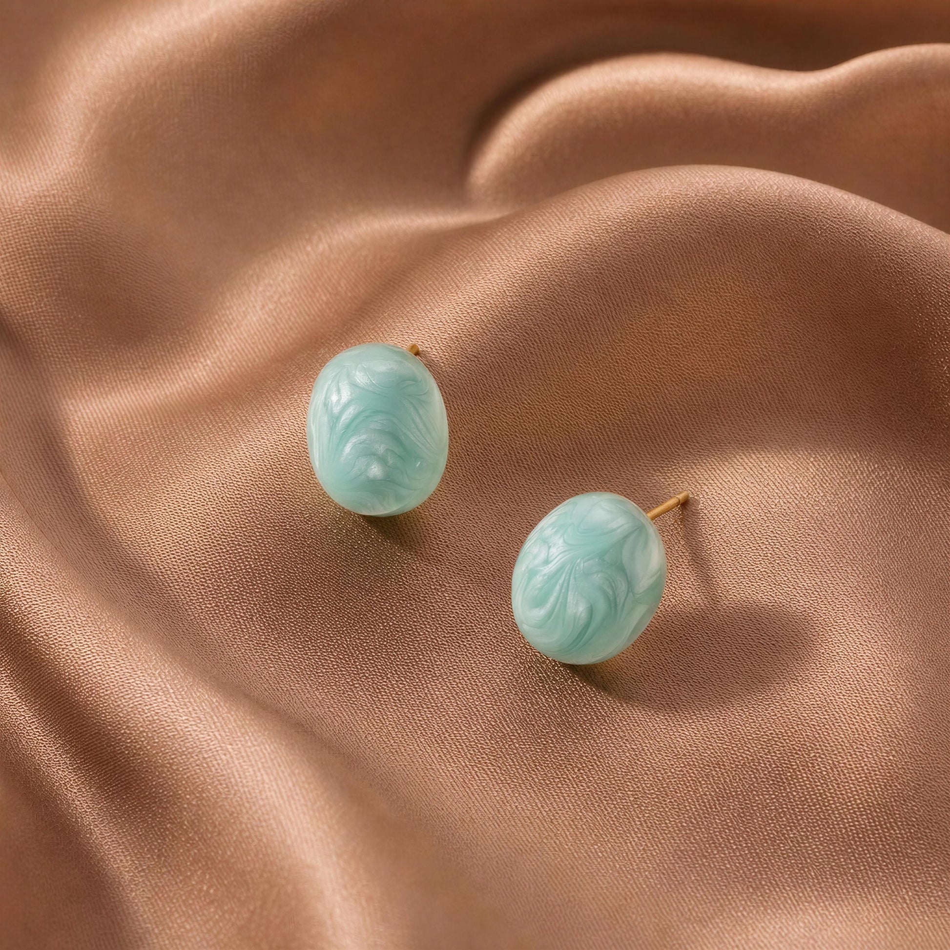 Pair of turquoise earrings on a beige fabric background
