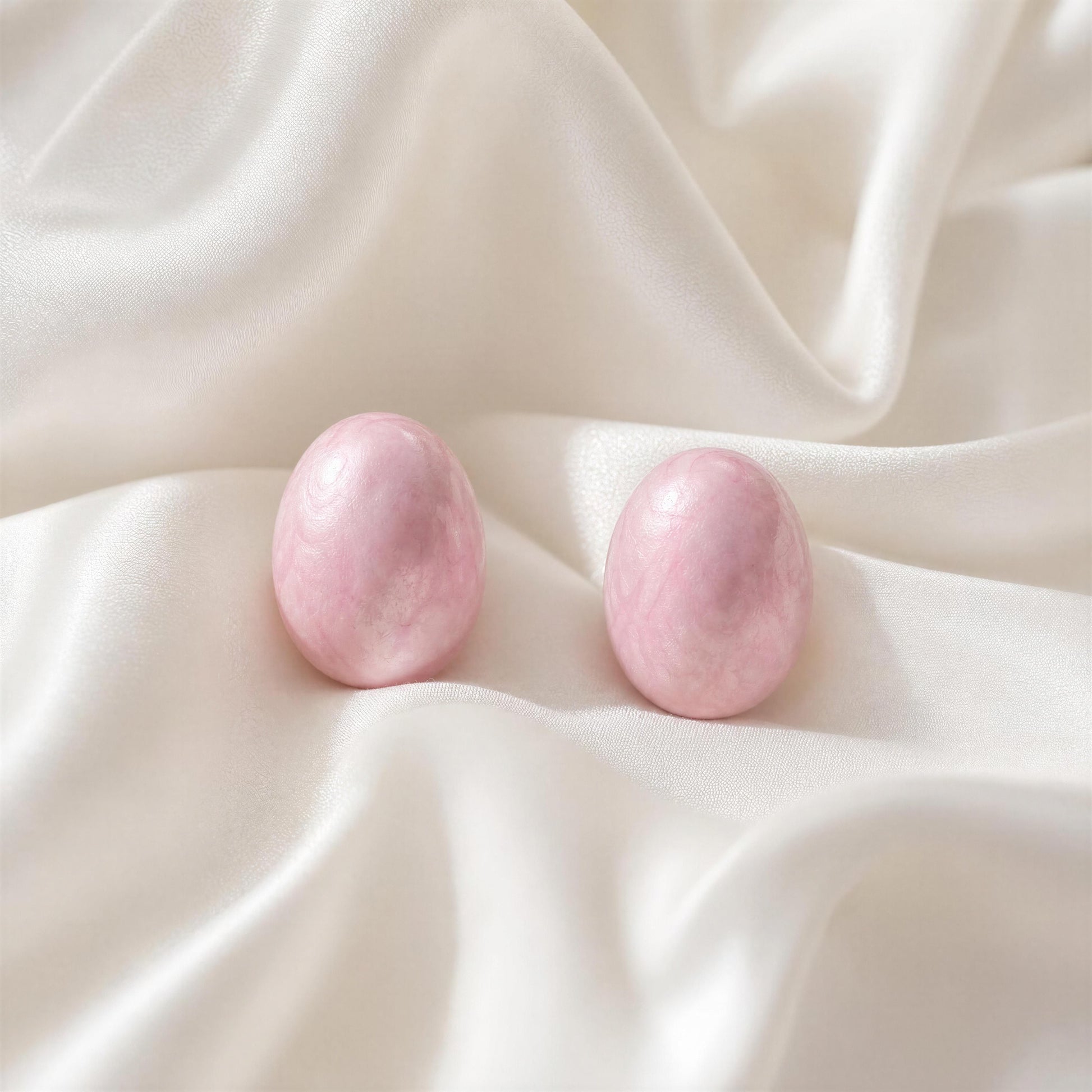 Pink stone earrings on a soft white fabric background