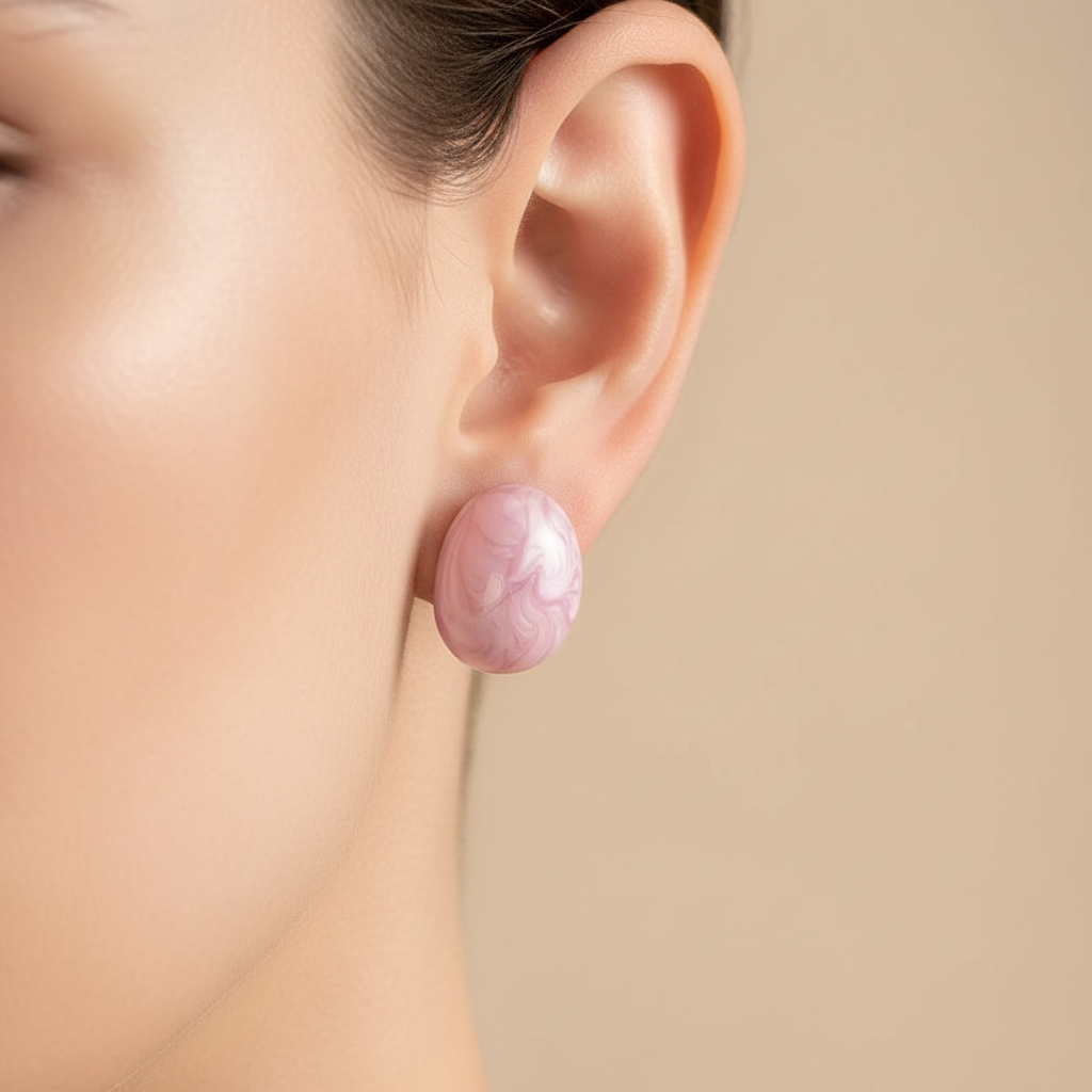 Close-up of an ear wearing the p Chica Chica Jewelry pink earrings against a beige background