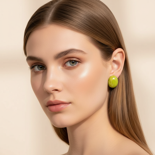 Model wearing Rosina Studs in Verde Luxe, glossy marbled green oval stud earrings in a minimalist luxury portrait.