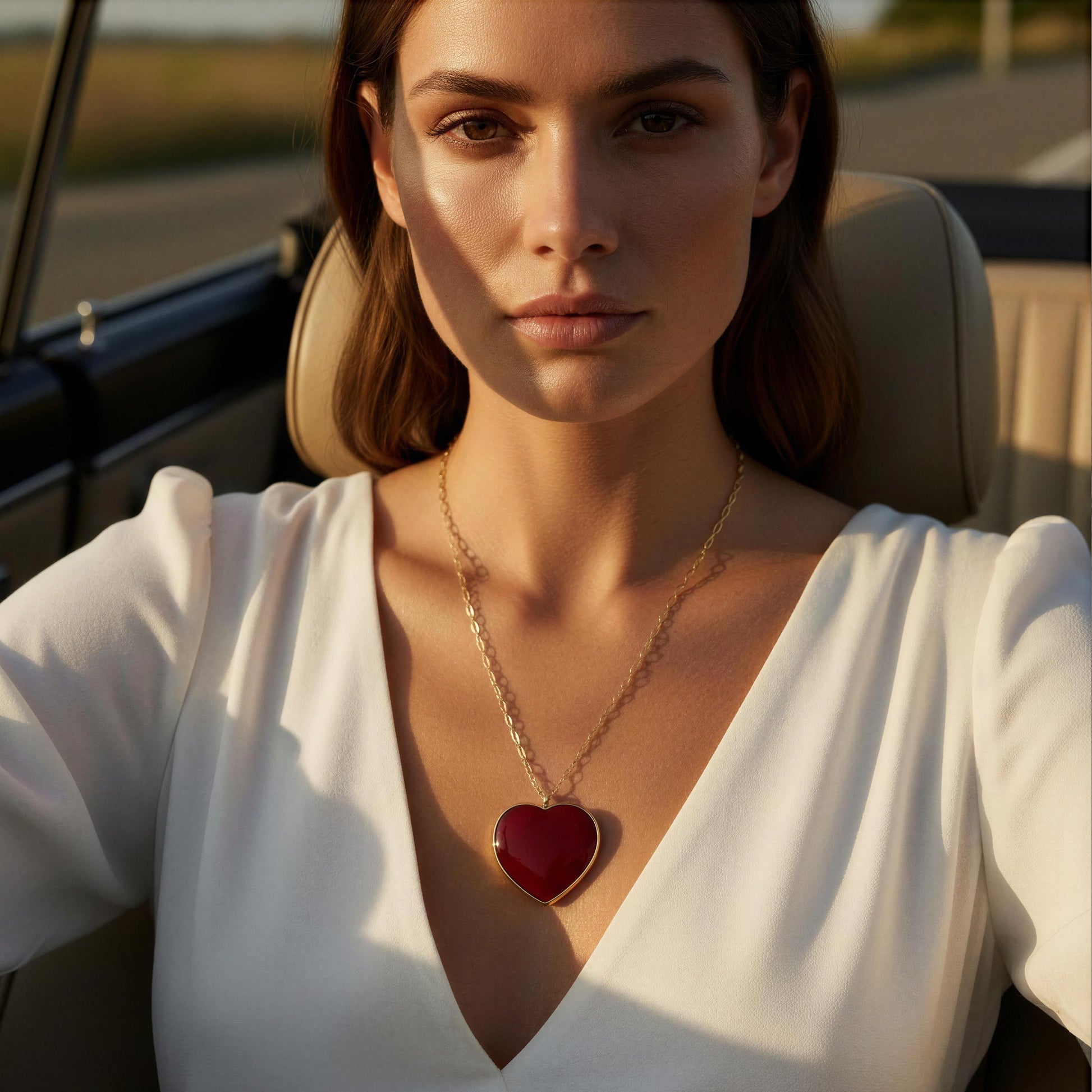 Woman wearing the Rosso Heart Necklace with a red heart pendant in a car.