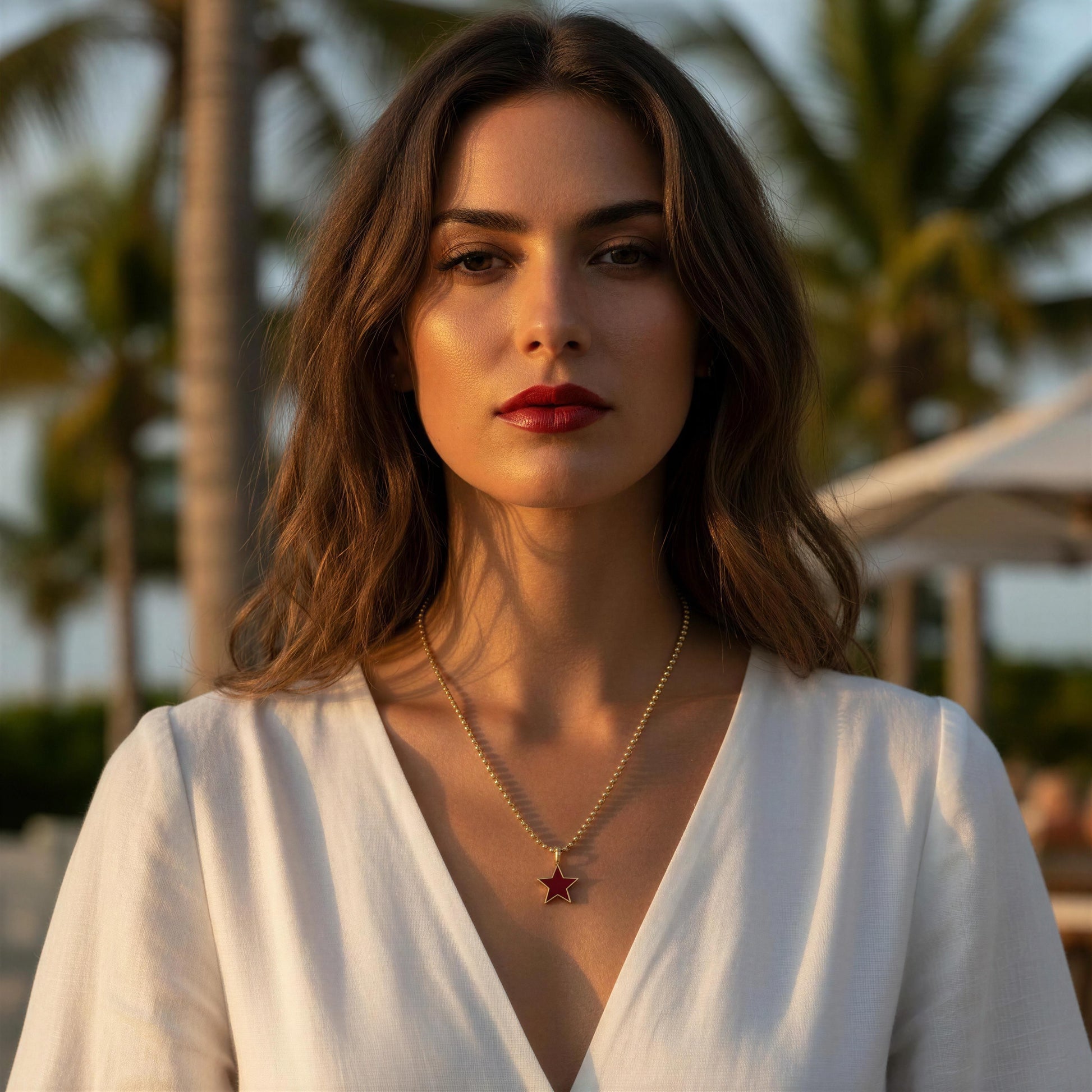 Woman wearing a white top with the the Scarlet Star Necklace in a tropical setting
