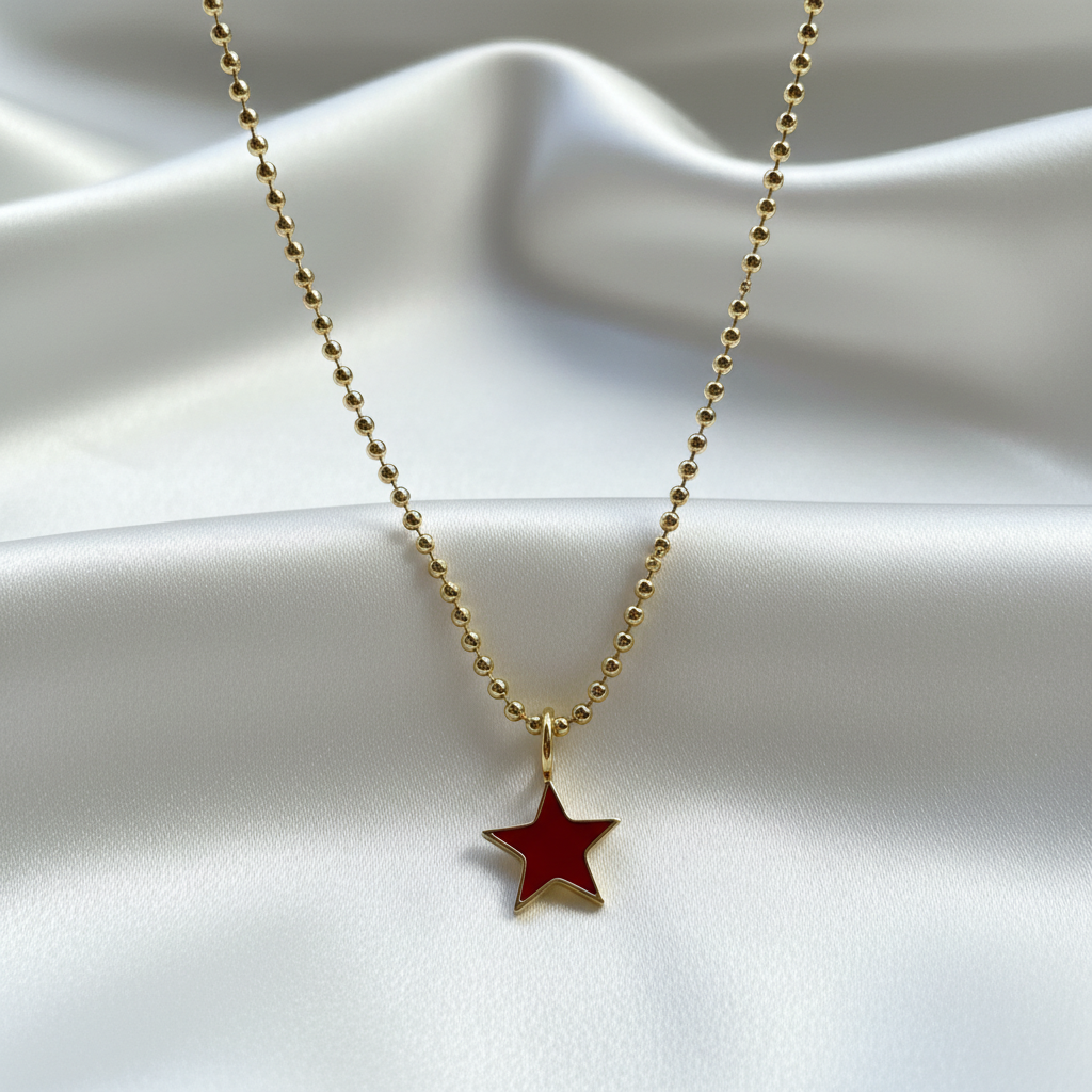 Scarlet Star Necklace with a red star pendant on a white fabric background